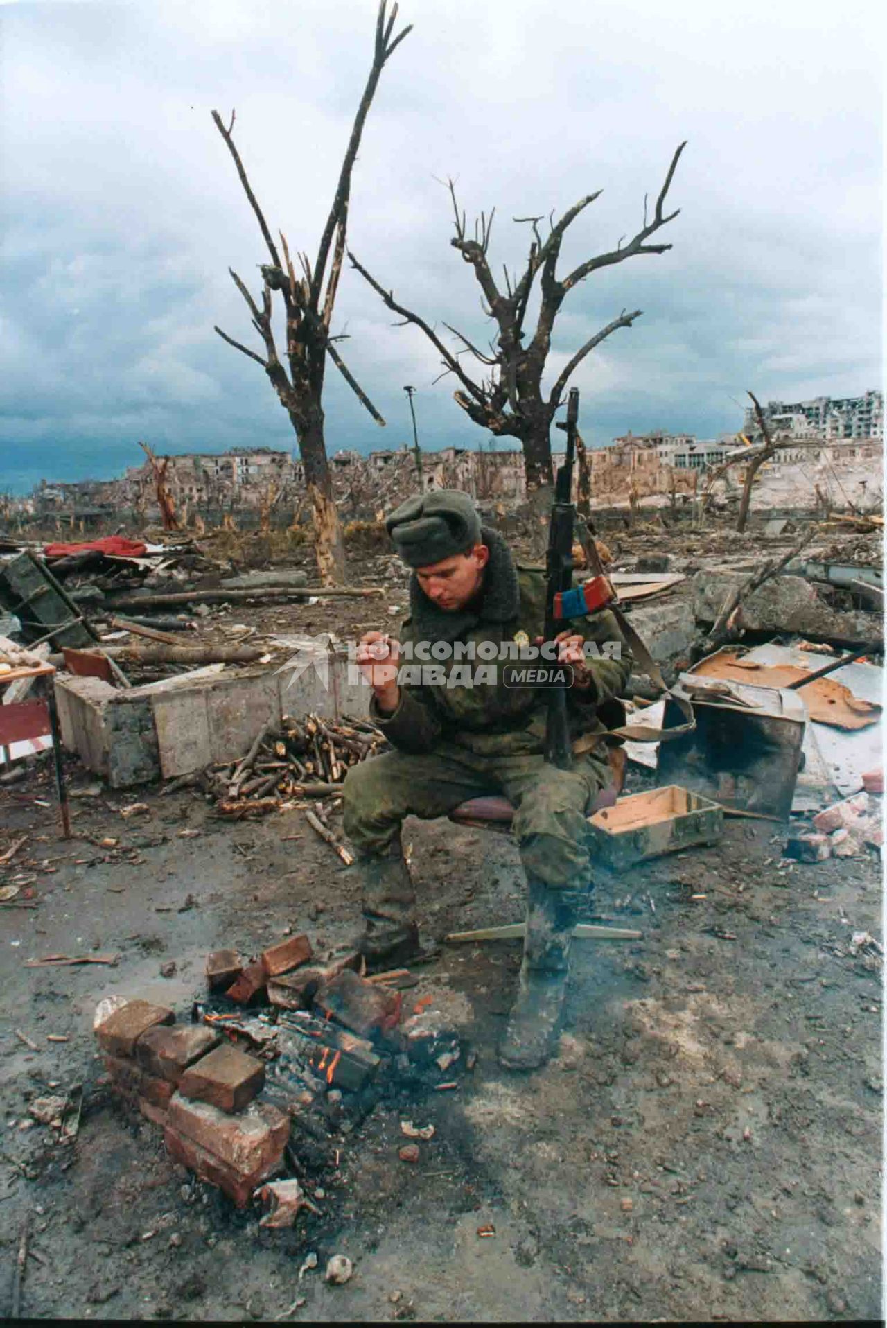 Первая Чеченская война. 1995г. Солдат российской армии курит у костра в центре разрушенного Грозного.