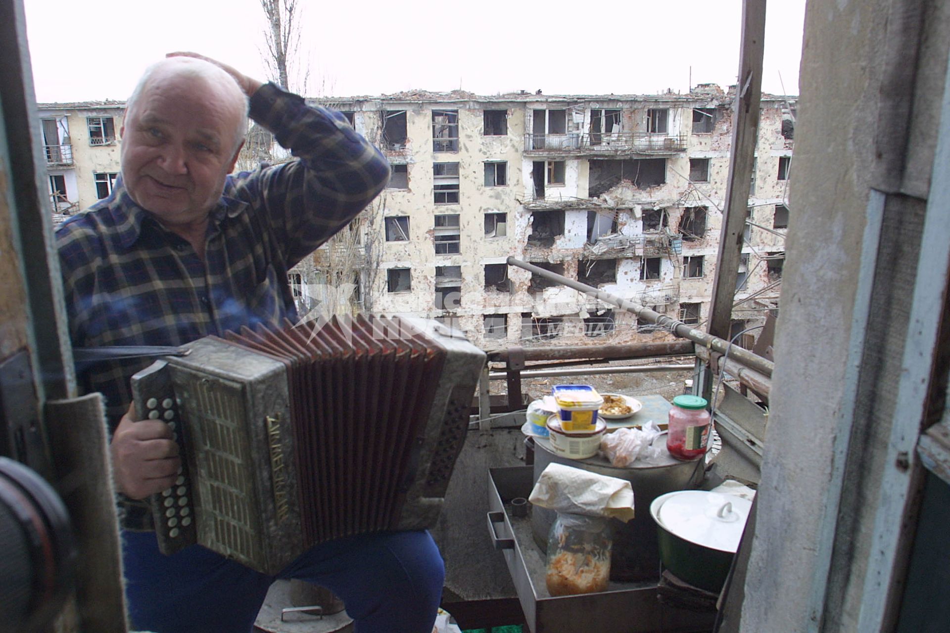 Чечня. Грозный. Русский мужчина играет на баяне на балконе своей квартиры.
