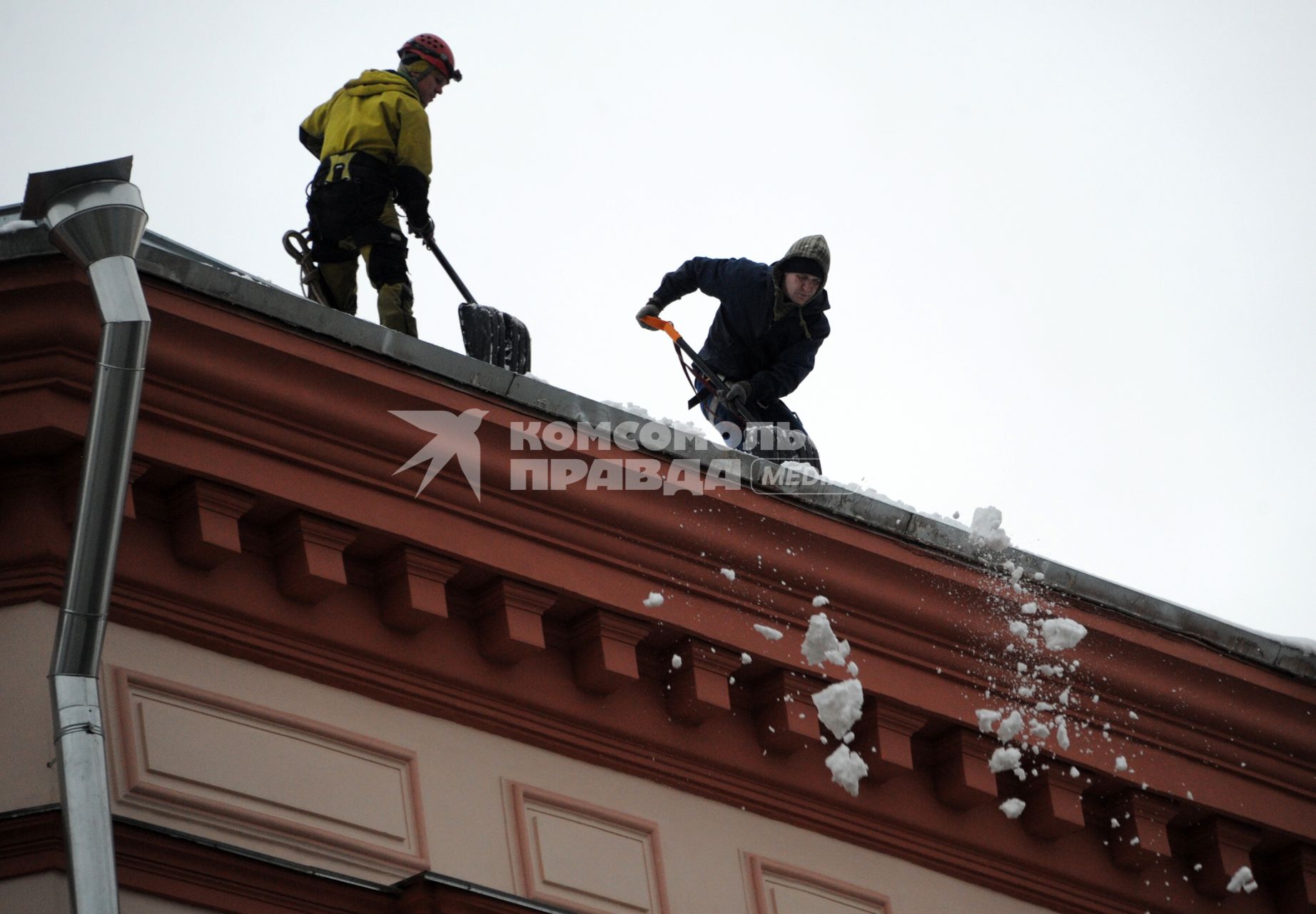 Москва. Сотрудники коммунальной службы счищают снег с крыши дома.