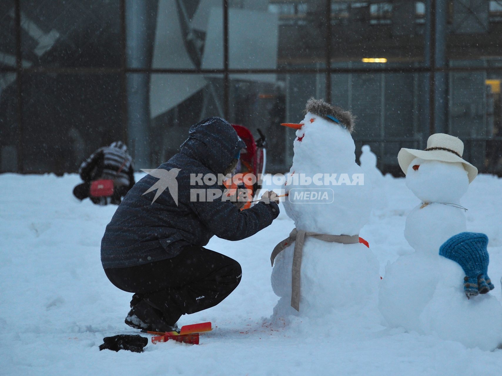 Москва. Женщина украшает снеговика.