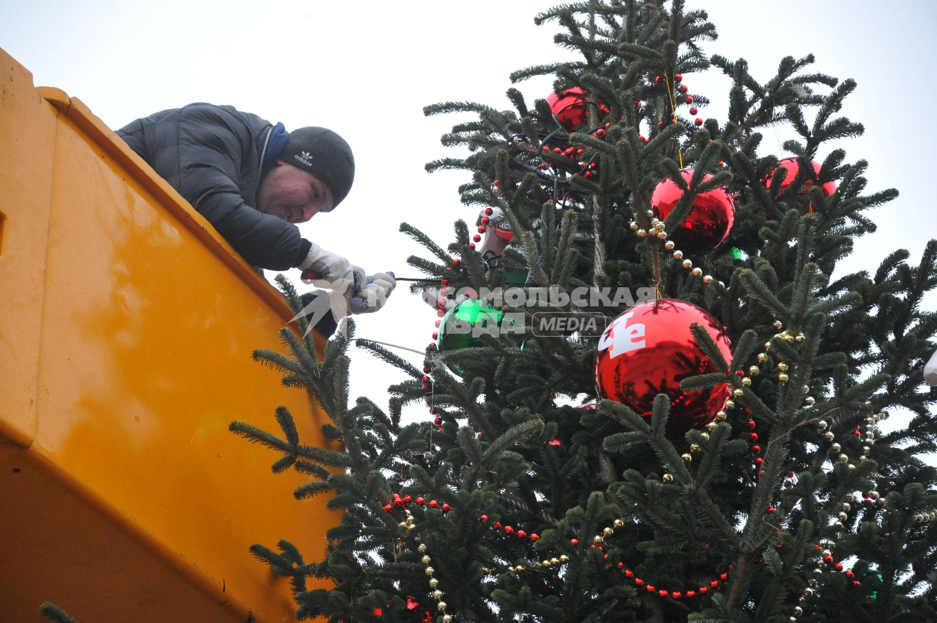 Москва.  Мужчина украшает новогоднюю елку.