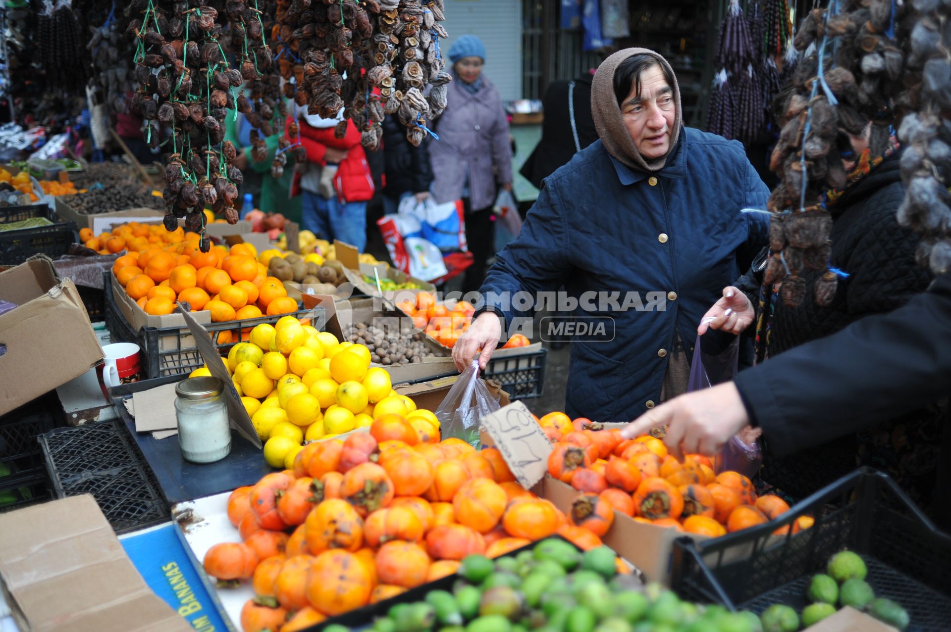Абхазия. Сухум. Женщина покупает мандарины на рынке.