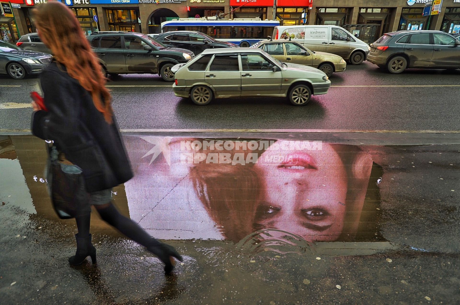 Москва.  Отражение девушки в луже на Новом Арбате.