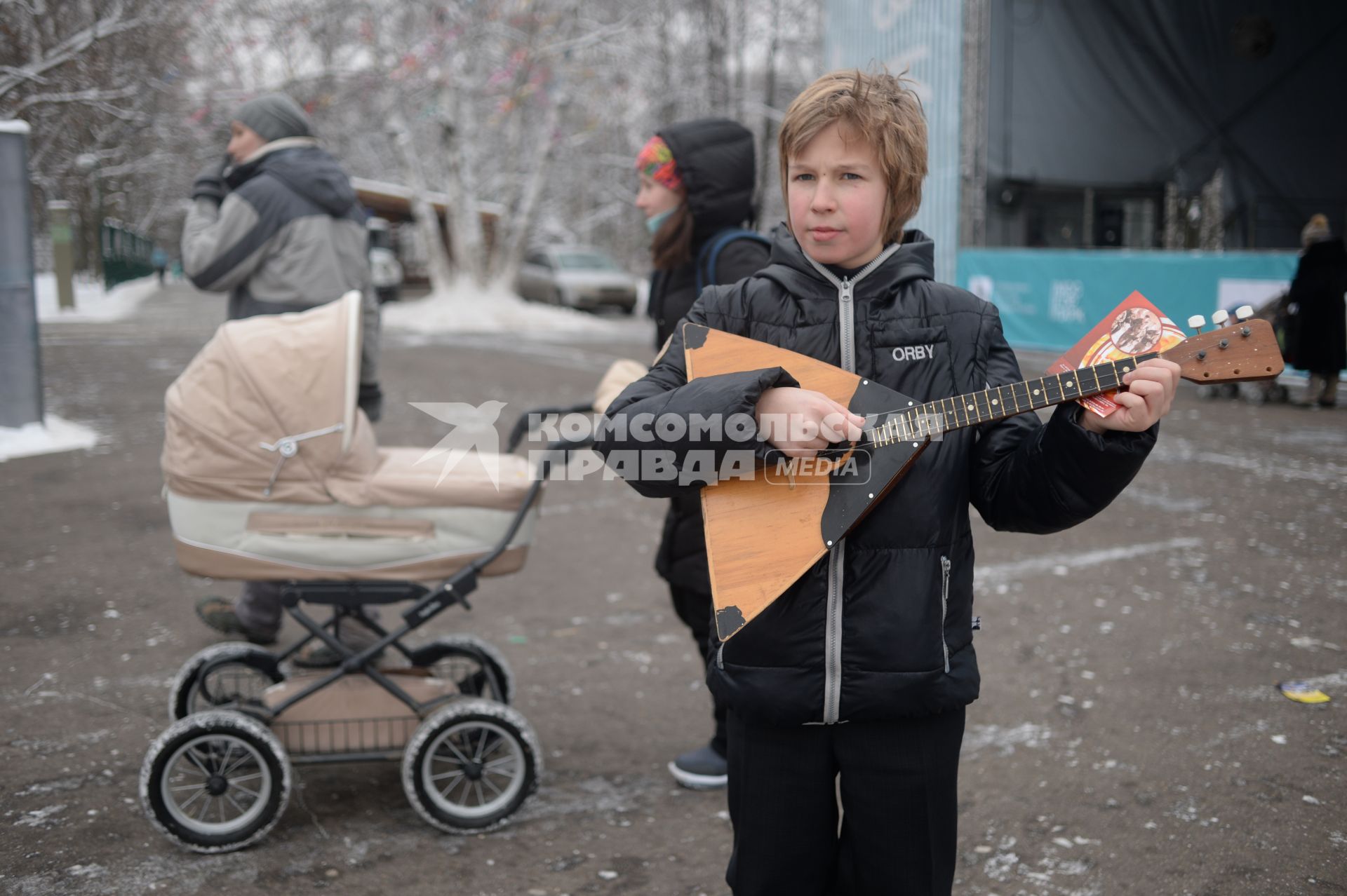 Москва. Ребенок играет на балалайке в парке Кузьминки.