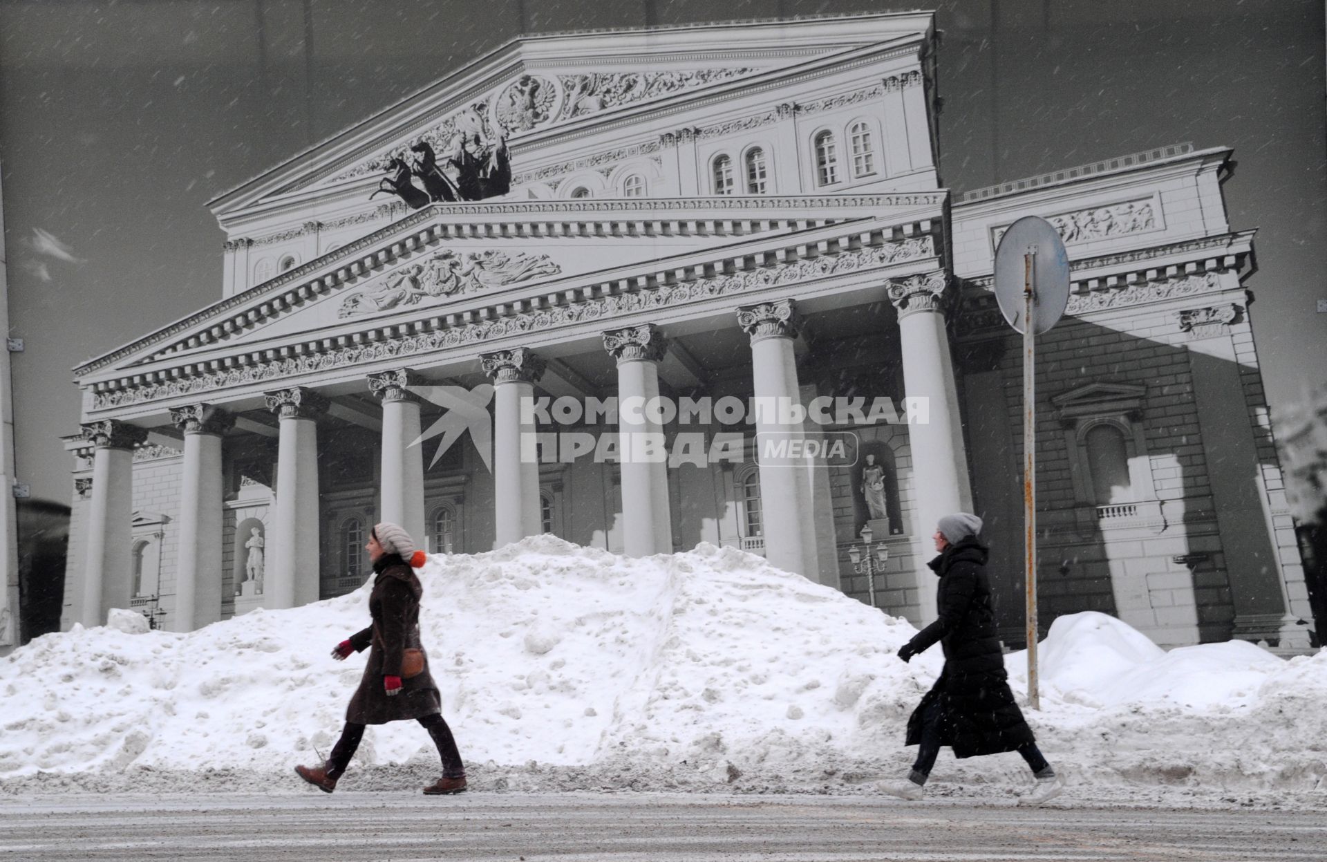 Москва. Люди идут мимо плаката с изображением Большого театра.