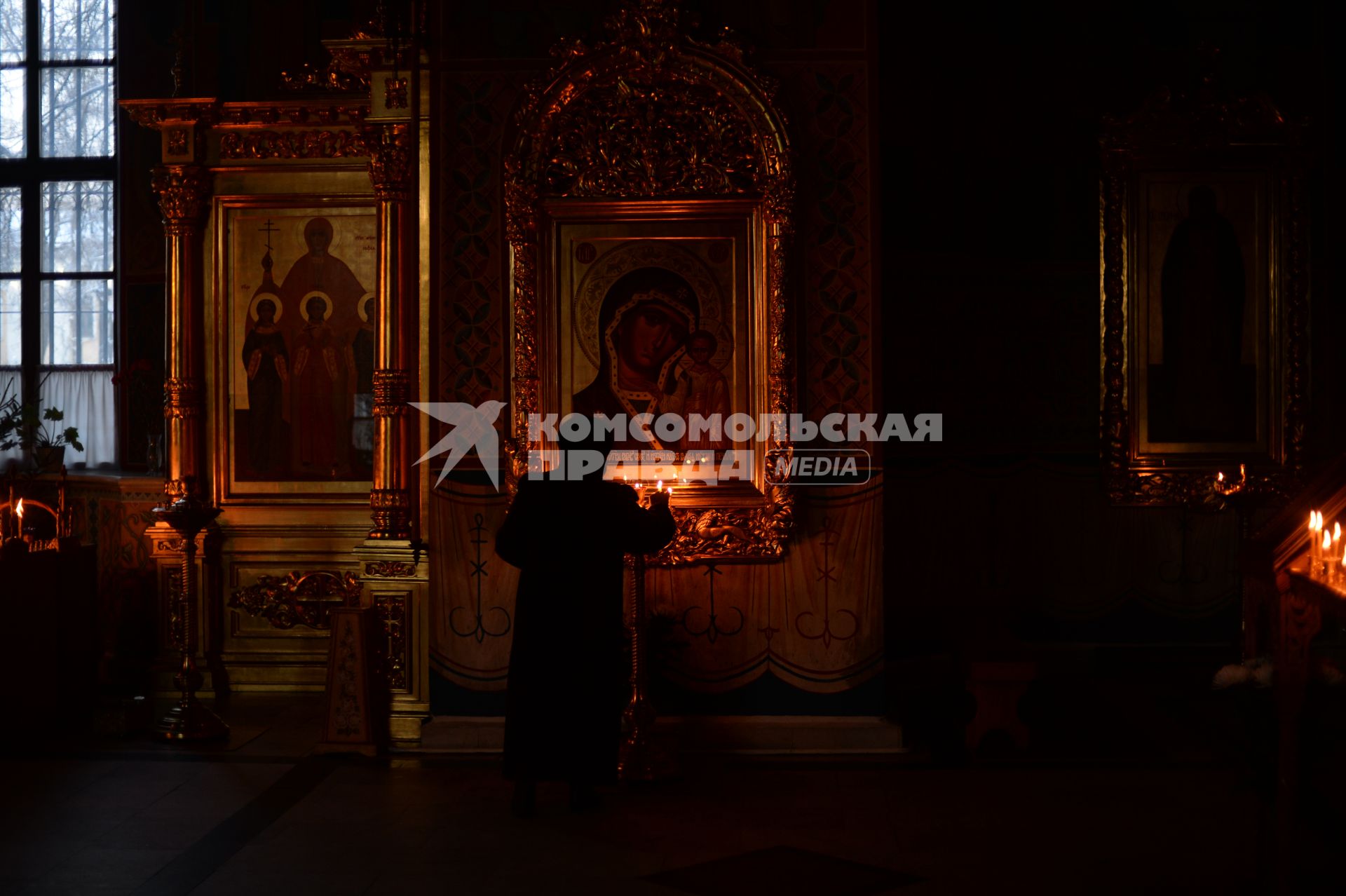 Калуга. Женщина ставит свечку Иконе Богородице в храме.