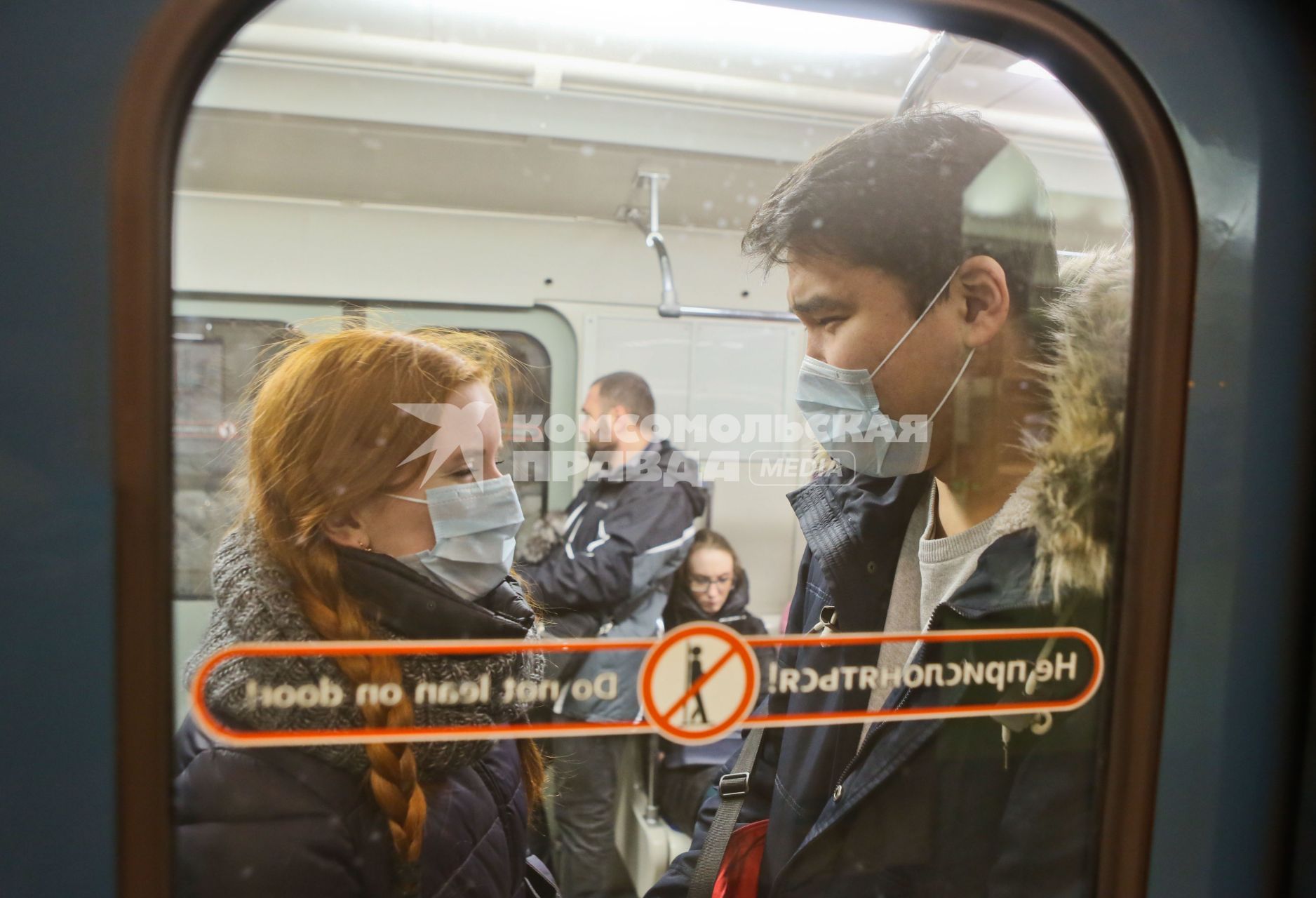 Санкт-Петербург. Молодые люди в медицинских масках в вагоне поезда.