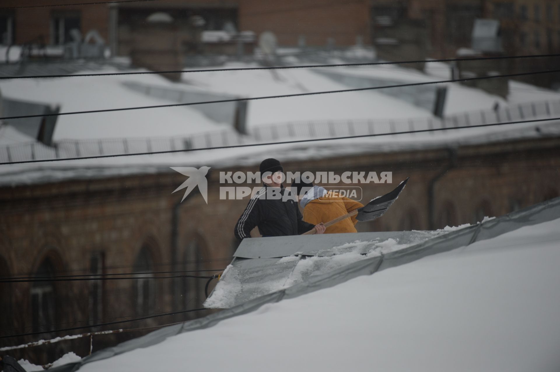 Москва. Сотрудники коммунальной службы счищают снег с крыши дома.