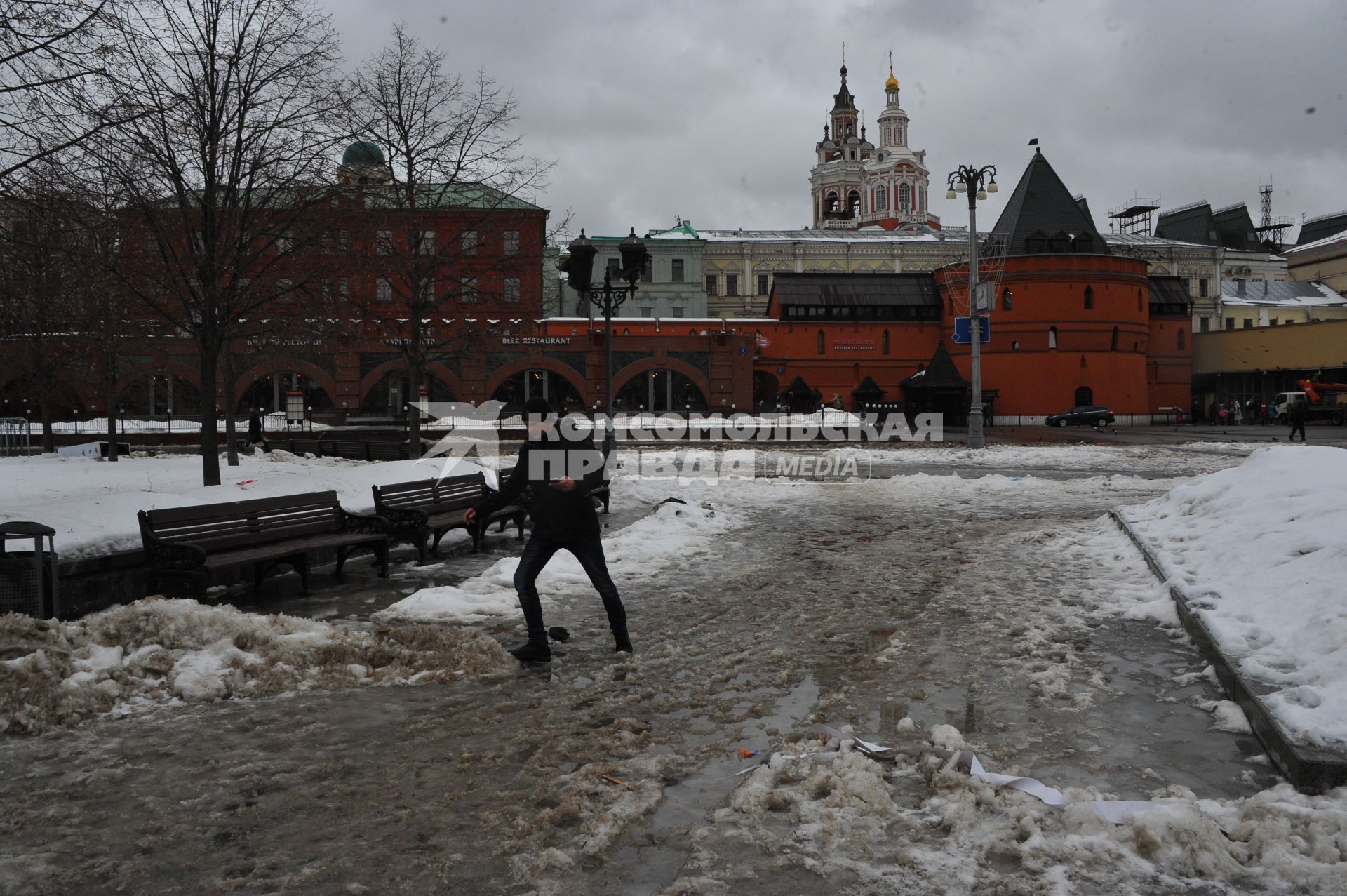 Москва.   Мужчина обходит лужи на Театральной площади.