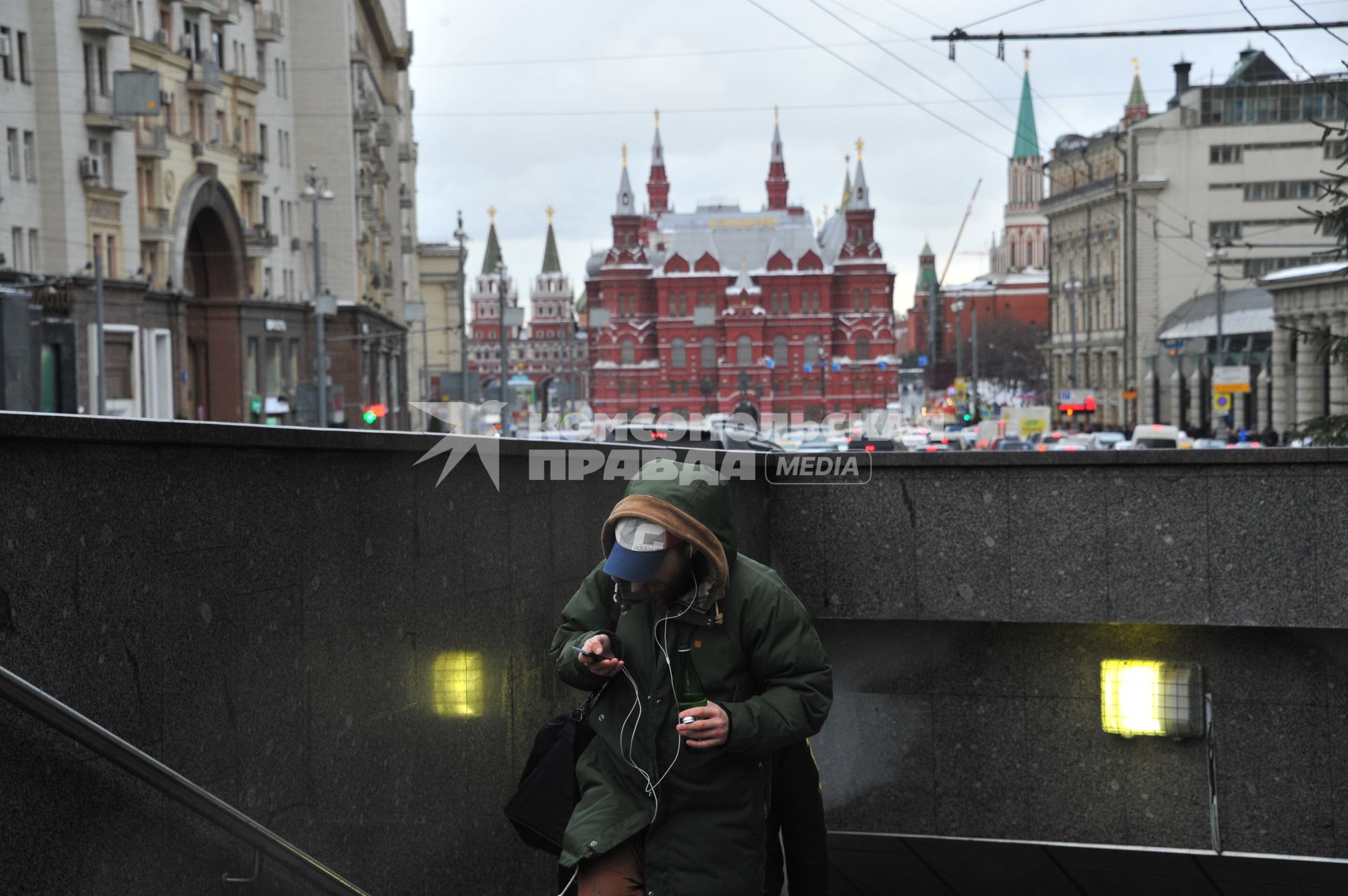 Москва.   Молодой человек с мобильным телефоном выходит из подземного перехода на Тверской улице.