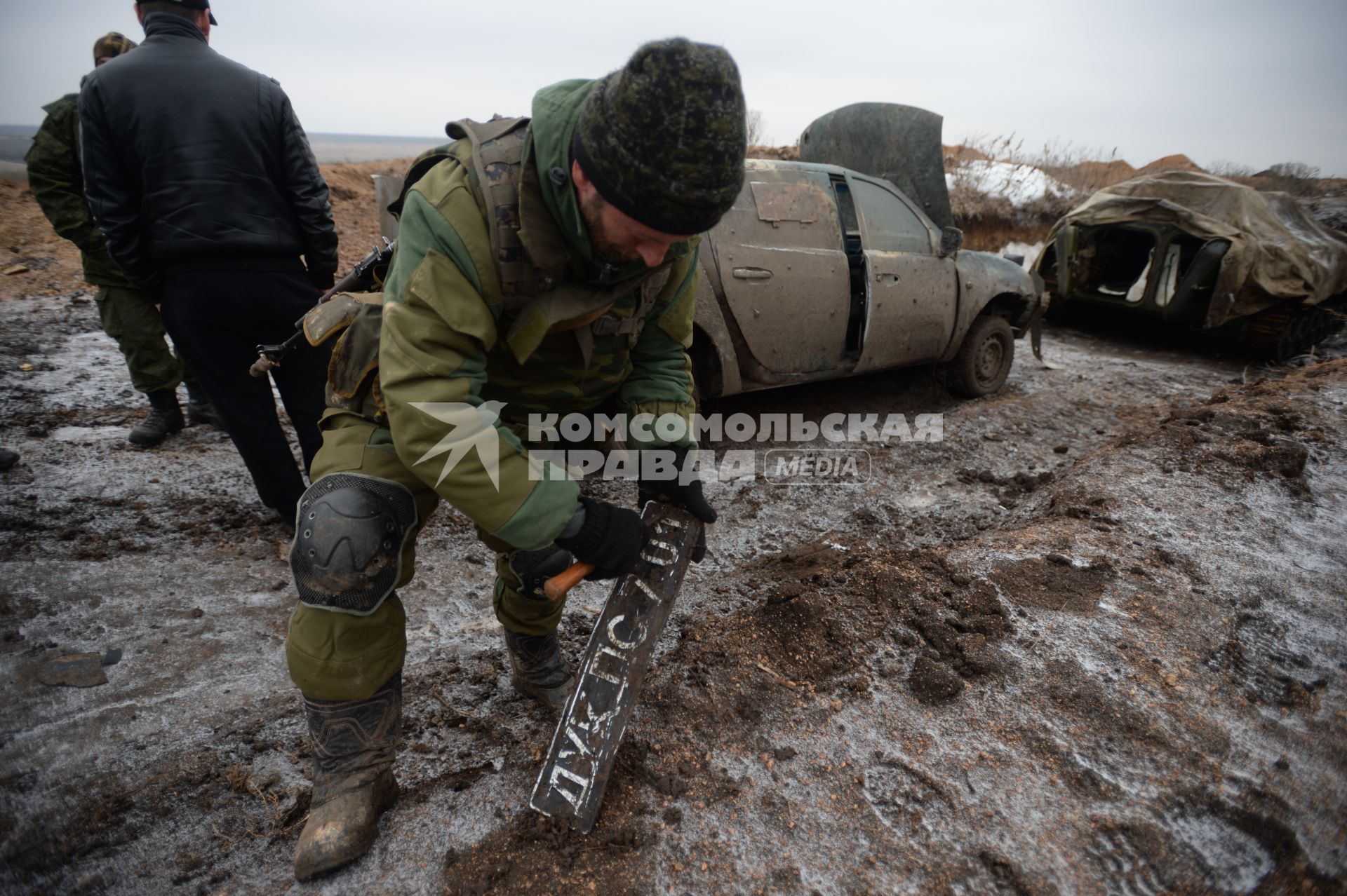 Украина. Донецкая область. Боевые позиции ополченцев ДНР. Боец отряда `Викинг` очищает от грязи автомобильный номер, принадлежащий машине украинской праворадикальной огранизации `Правый сектор`.