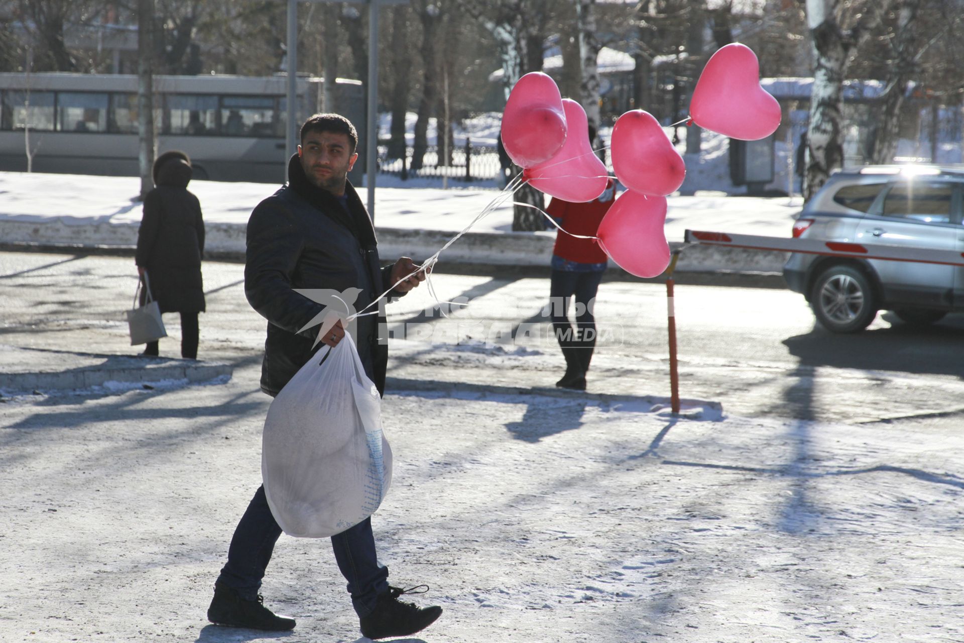 День Святого Валентина в Барнауле. Мужчина с пакетом и воздушными шариками `сердечками` идет по улице.