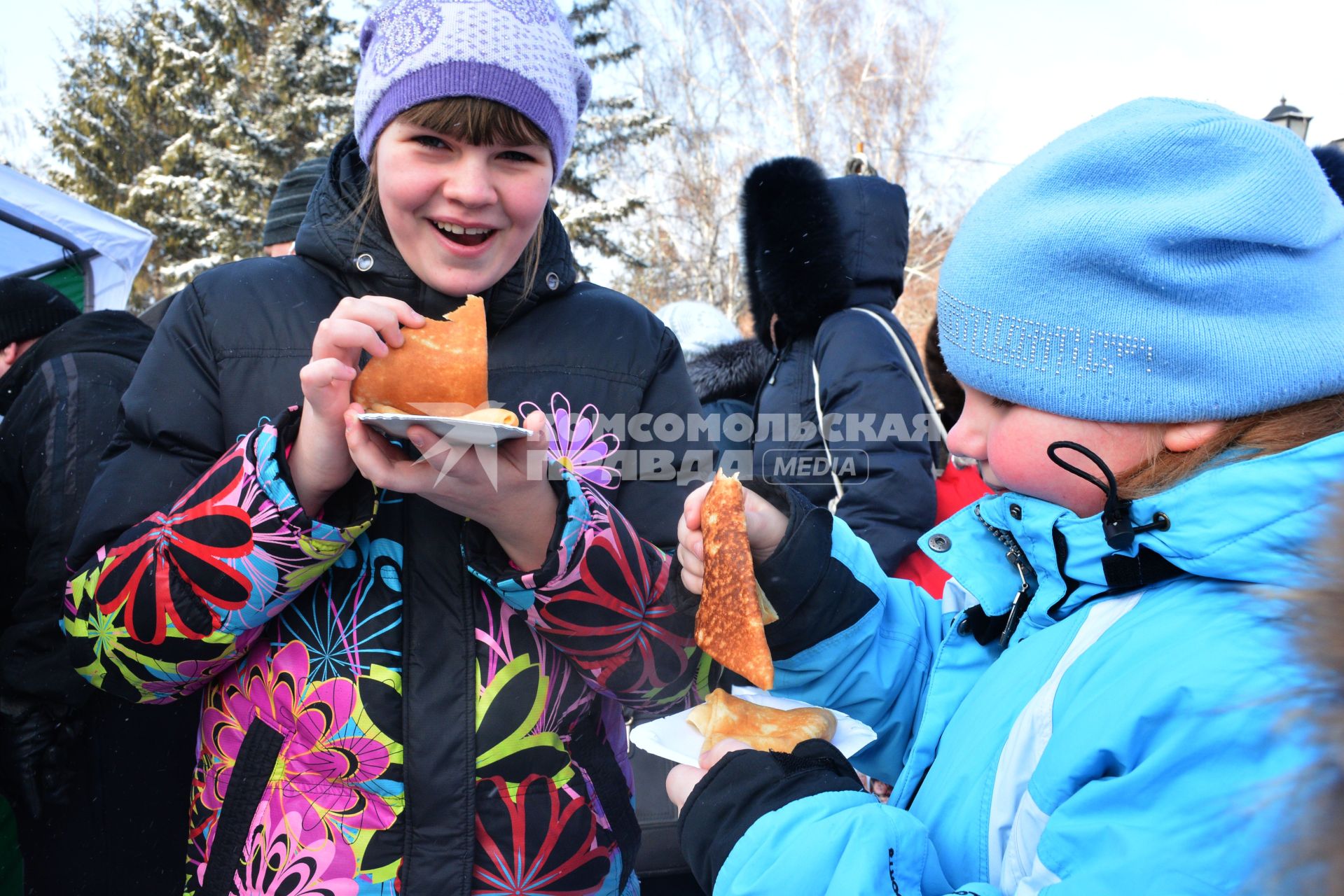 Масленица в Новосибирске. Девочки едят блины во время праздничных гуляний.