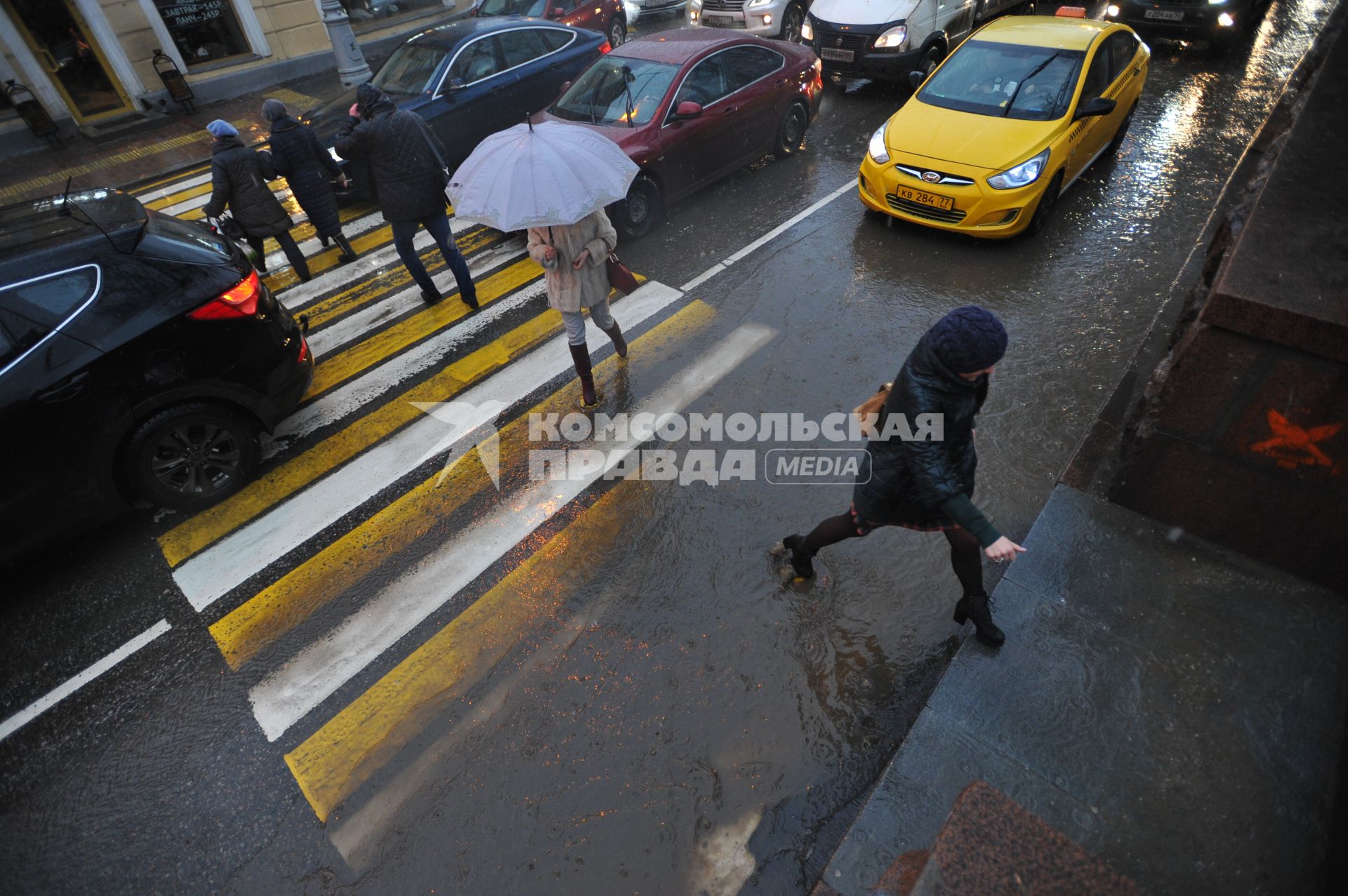 Москва.   Люди обходят лужу  на пешеходном переходе  на Гоголевском бульваре.