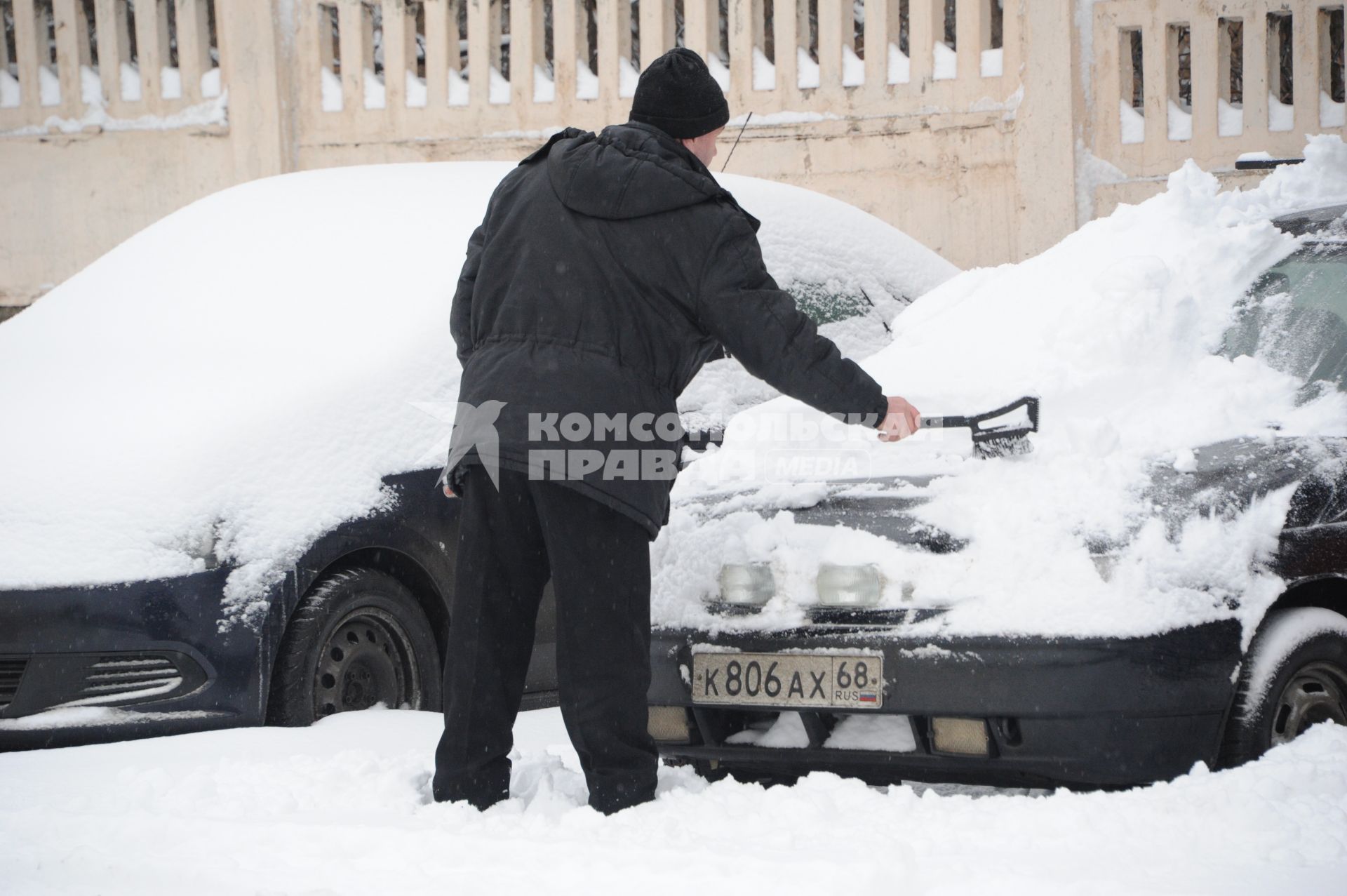 Москва.  Мужчина чистит свой автомобиль от снега на одной из улиц города.