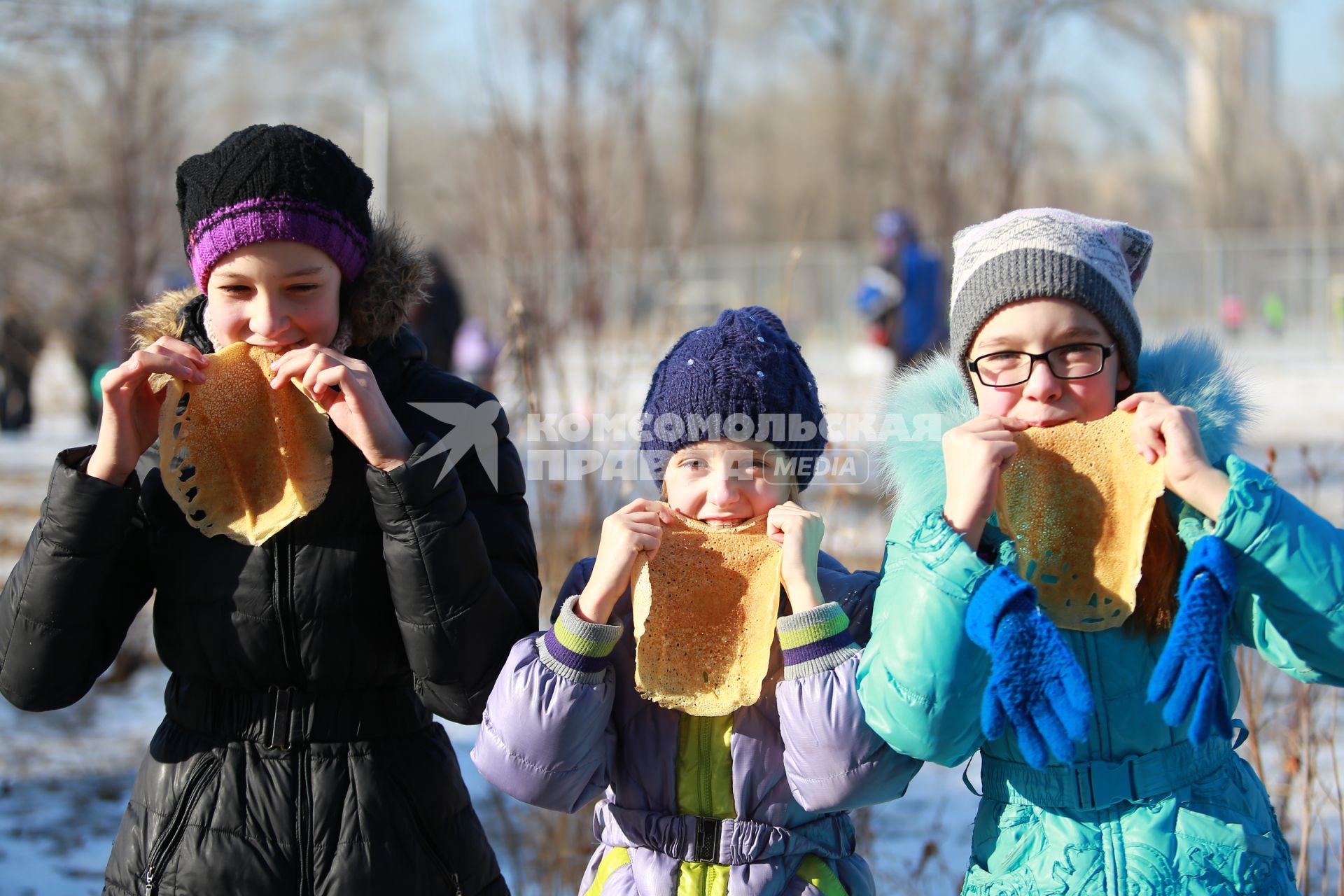 Красноярск. Девочки едят блины  на празднике Масленицы.