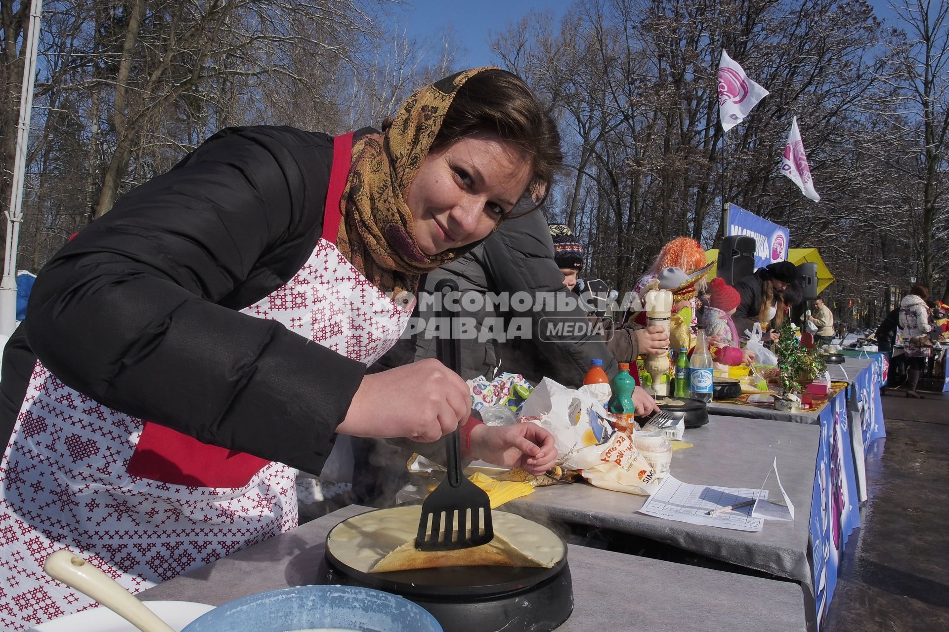 Тула.  Девушка печет блины во время праздника Широкой Масленицы.