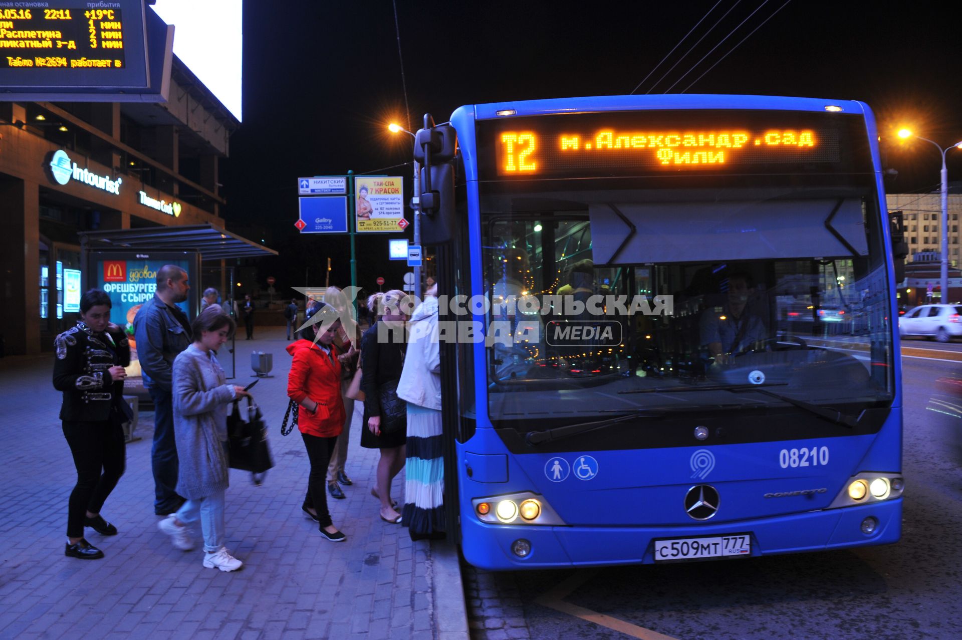 Москва. Пассажиры садятся в автобус на улице города.