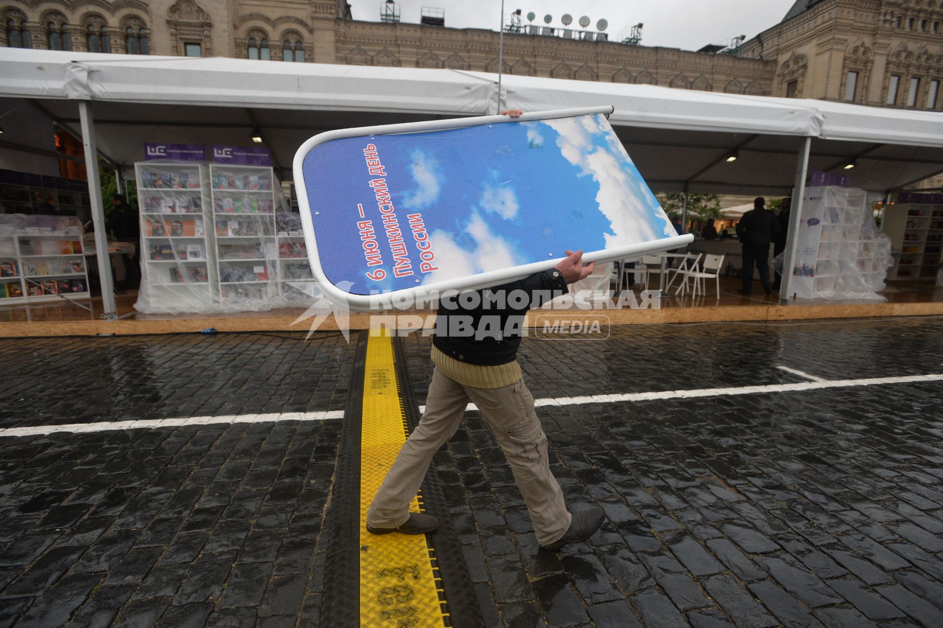 Москва. Мужчина укрылся от дождя рекламным щитом на книжном фестивале `Красная площадь`.