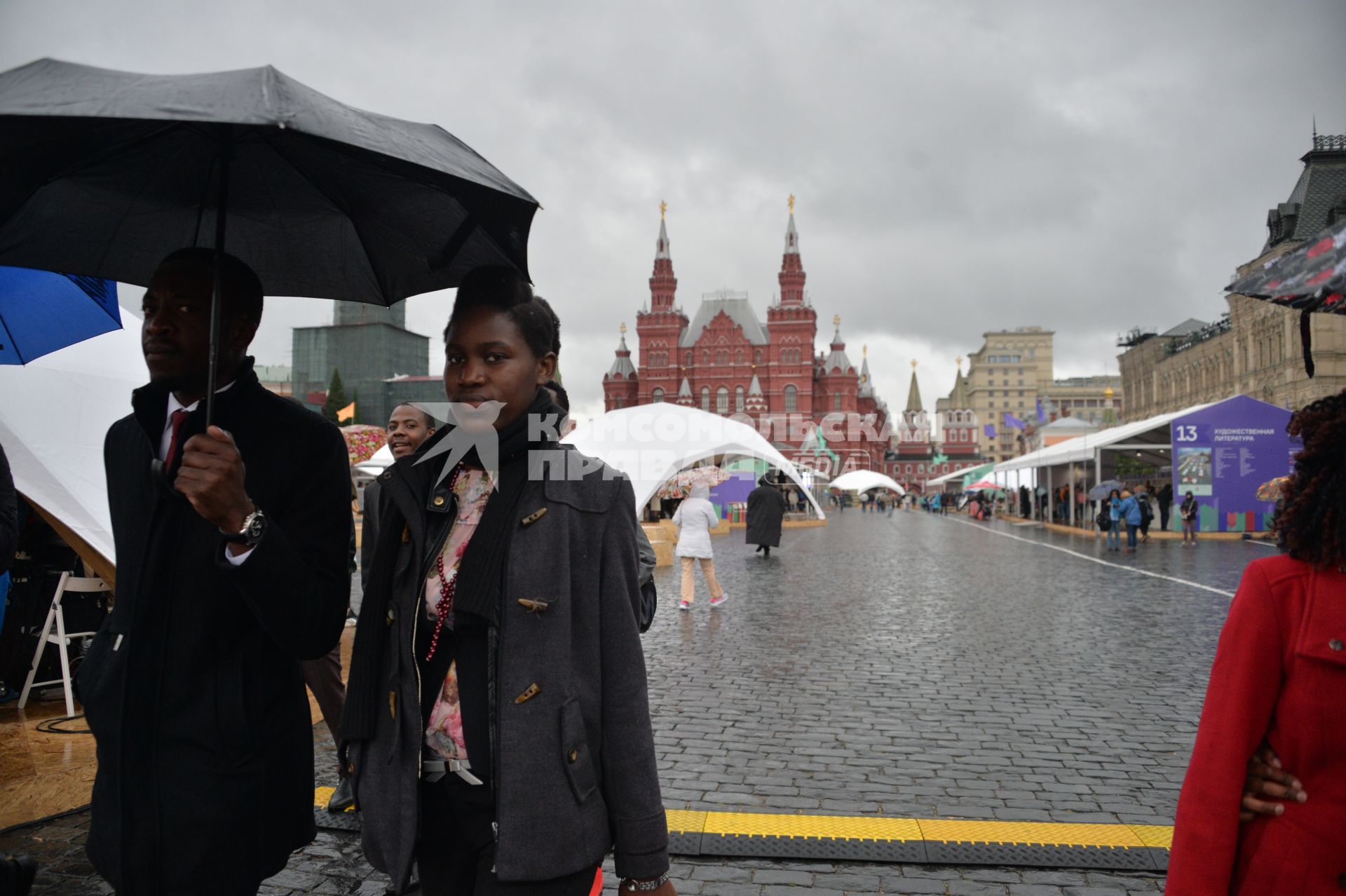 Москва. Прохожие  под зонтами на книжном фестивале `Красная площадь`.