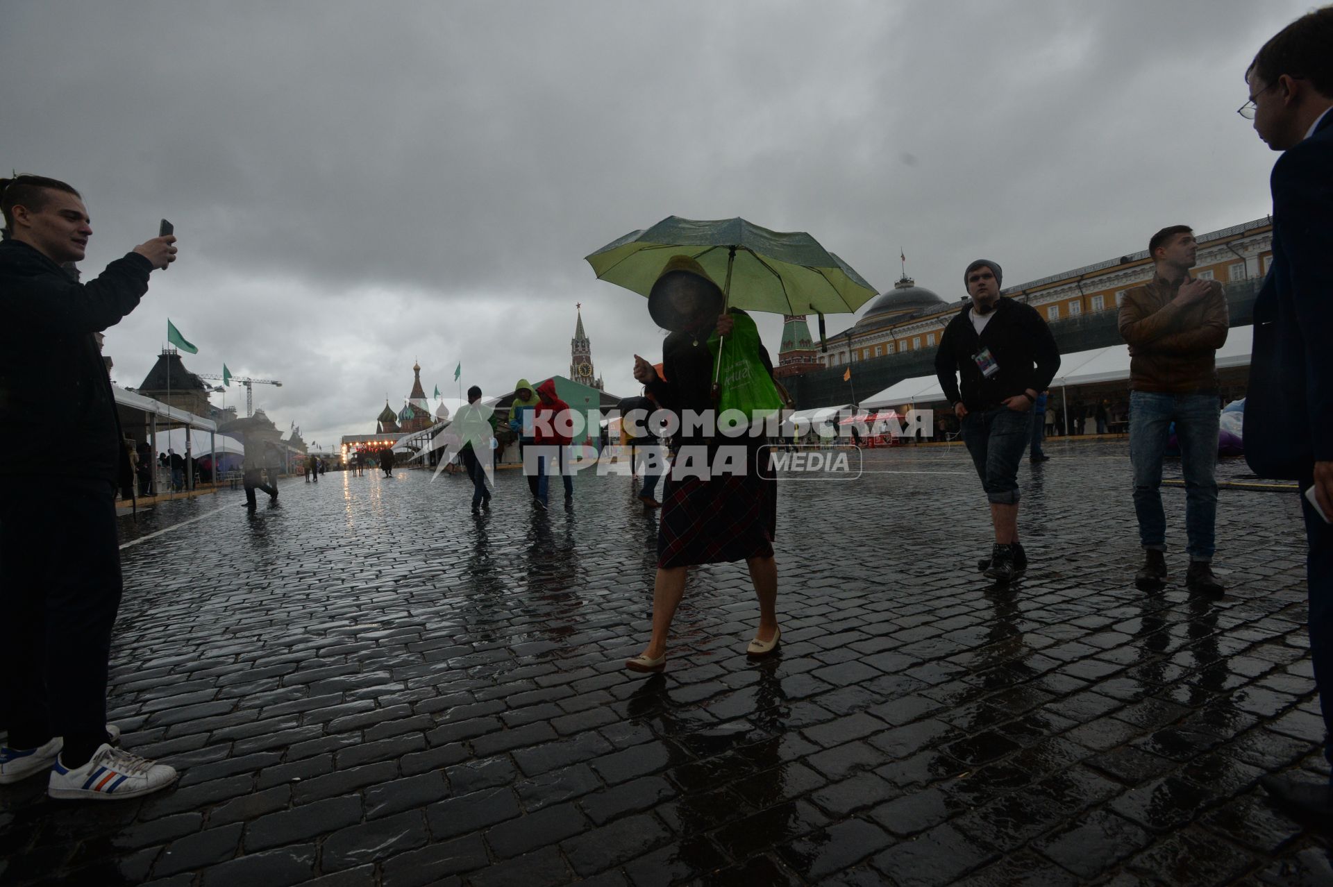 Москва. Прохожие  под зонтами на книжном фестивале `Красная площадь`.