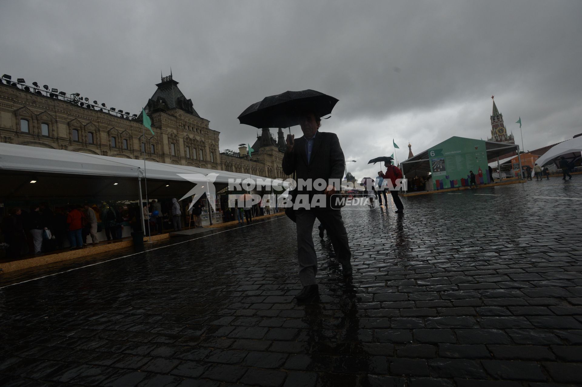 Москва. Прохожие  под зонтами на книжном фестивале `Красная площадь`.