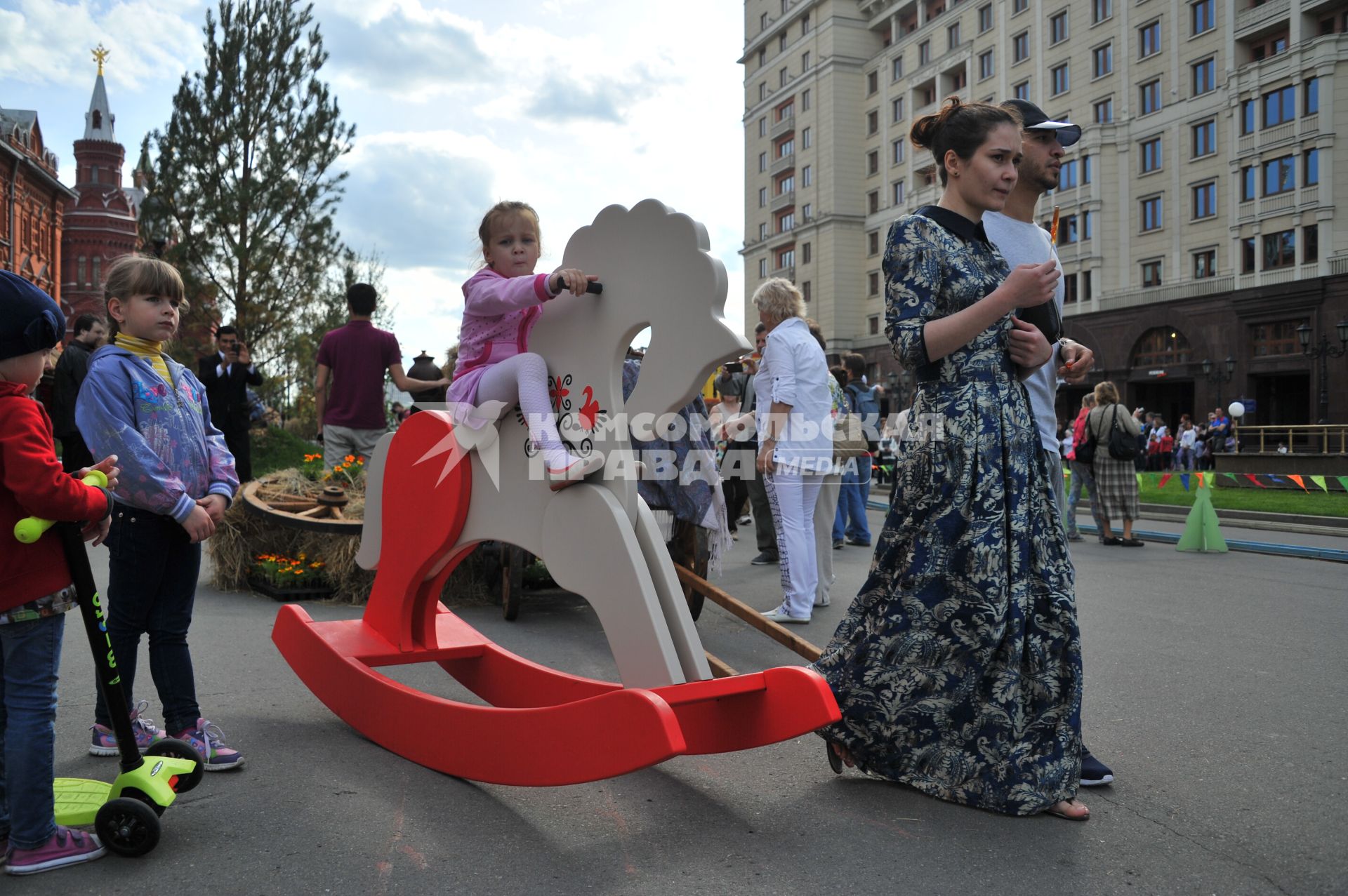 Москва.   Девочка качается на деревянной лошадке  на  историко-гастрономическом  фестивале `Наш продукт` в рамках уличных праздников `Московские сезоны` на Площади Революции.