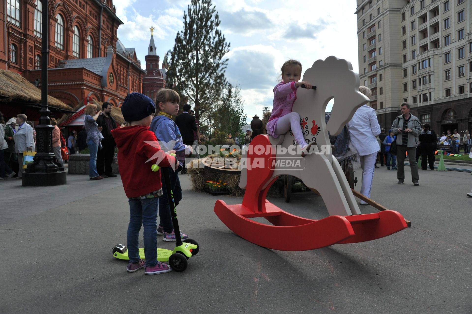 Москва.   Девочка качается на деревянной лошадке  на  историко-гастрономическом  фестивале `Наш продукт` в рамках уличных праздников `Московские сезоны` на Площади Революции.