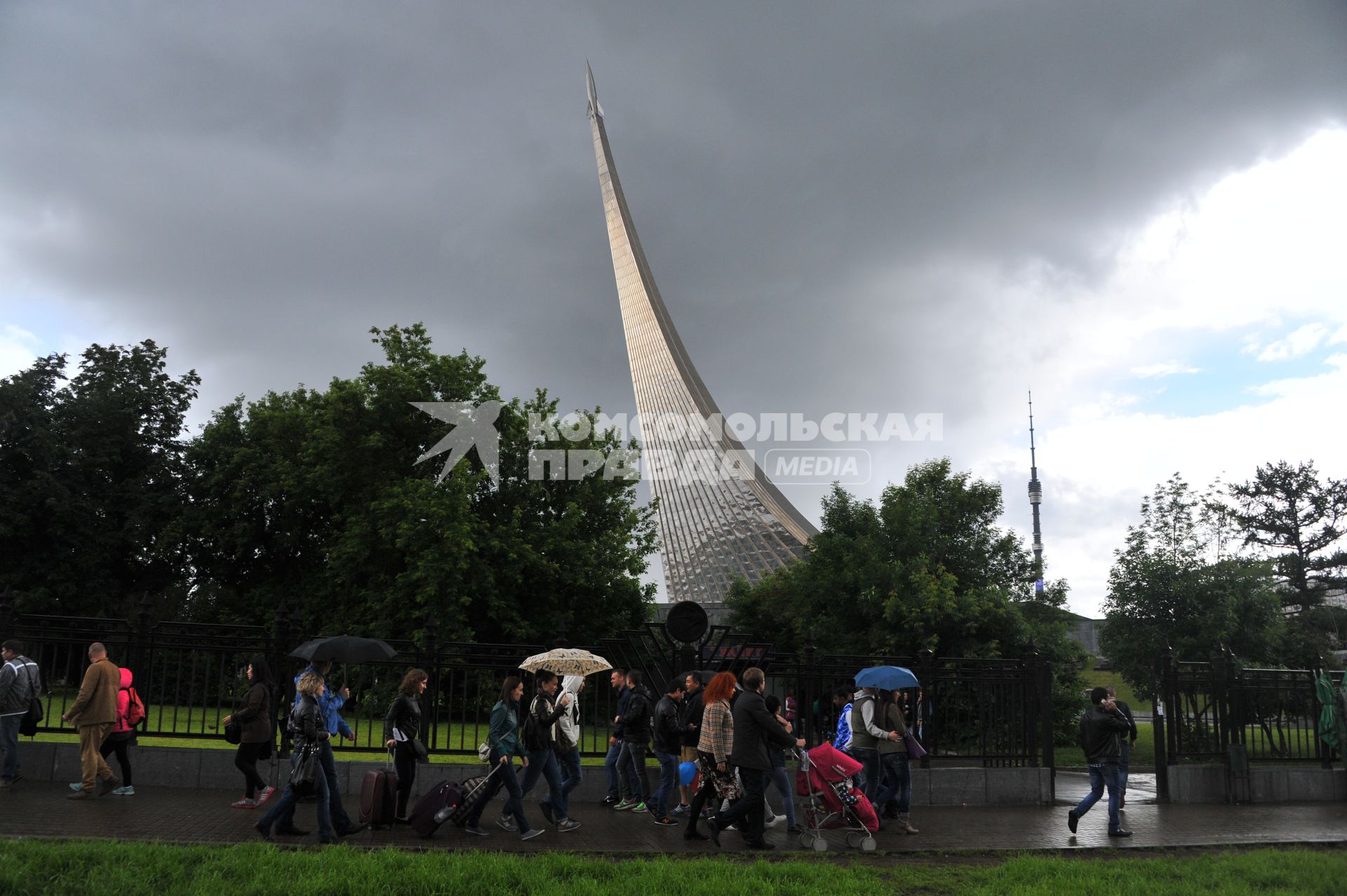 Москва.  Прохожие под дождем в районе станции метро ВДНХ около монумента `Покорителям космоса`.