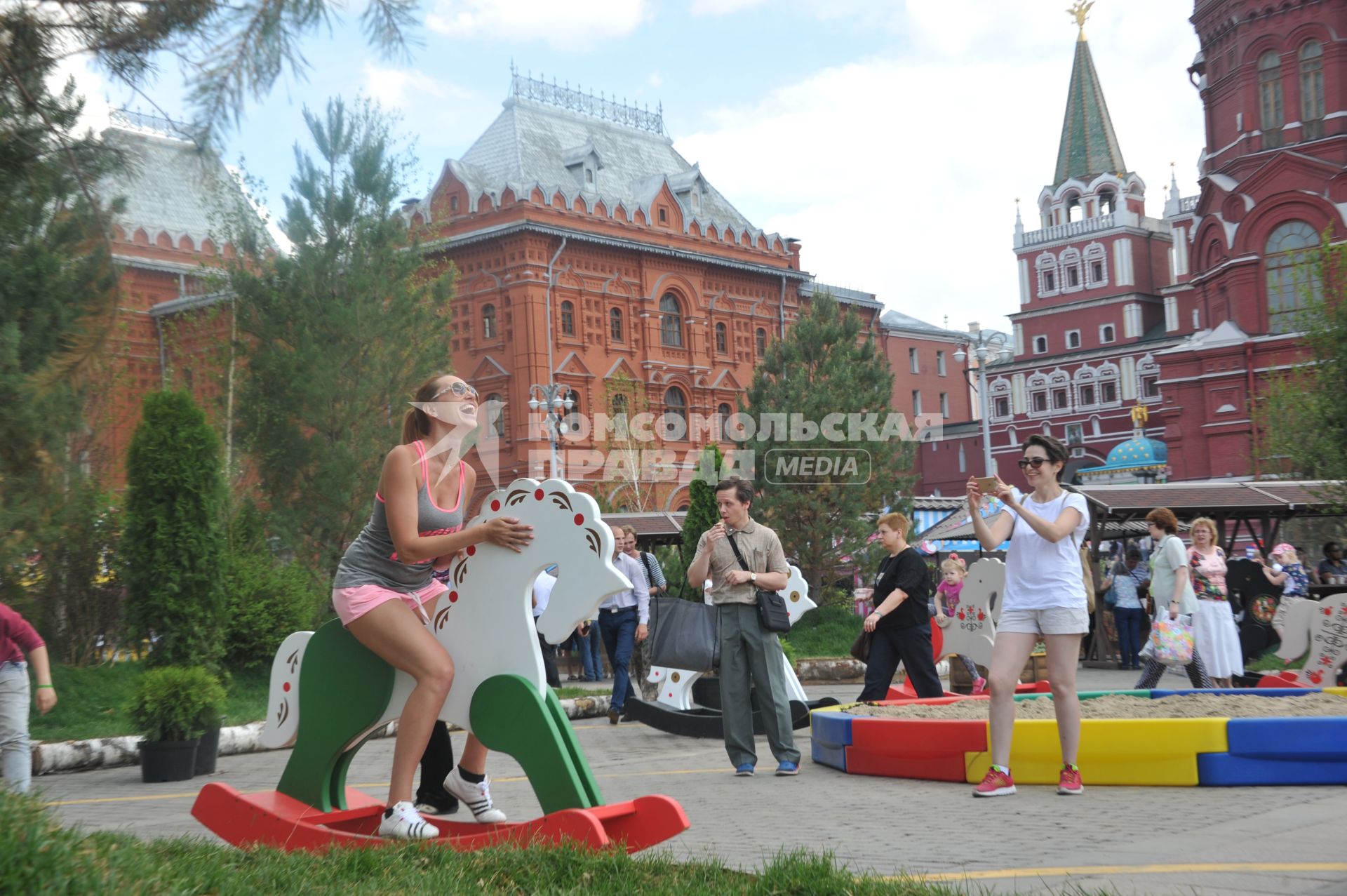 Москва.   Девушка качается на деревянной лошадке на Манежной площади, где проходит фестиваль `Московское мороженое`.