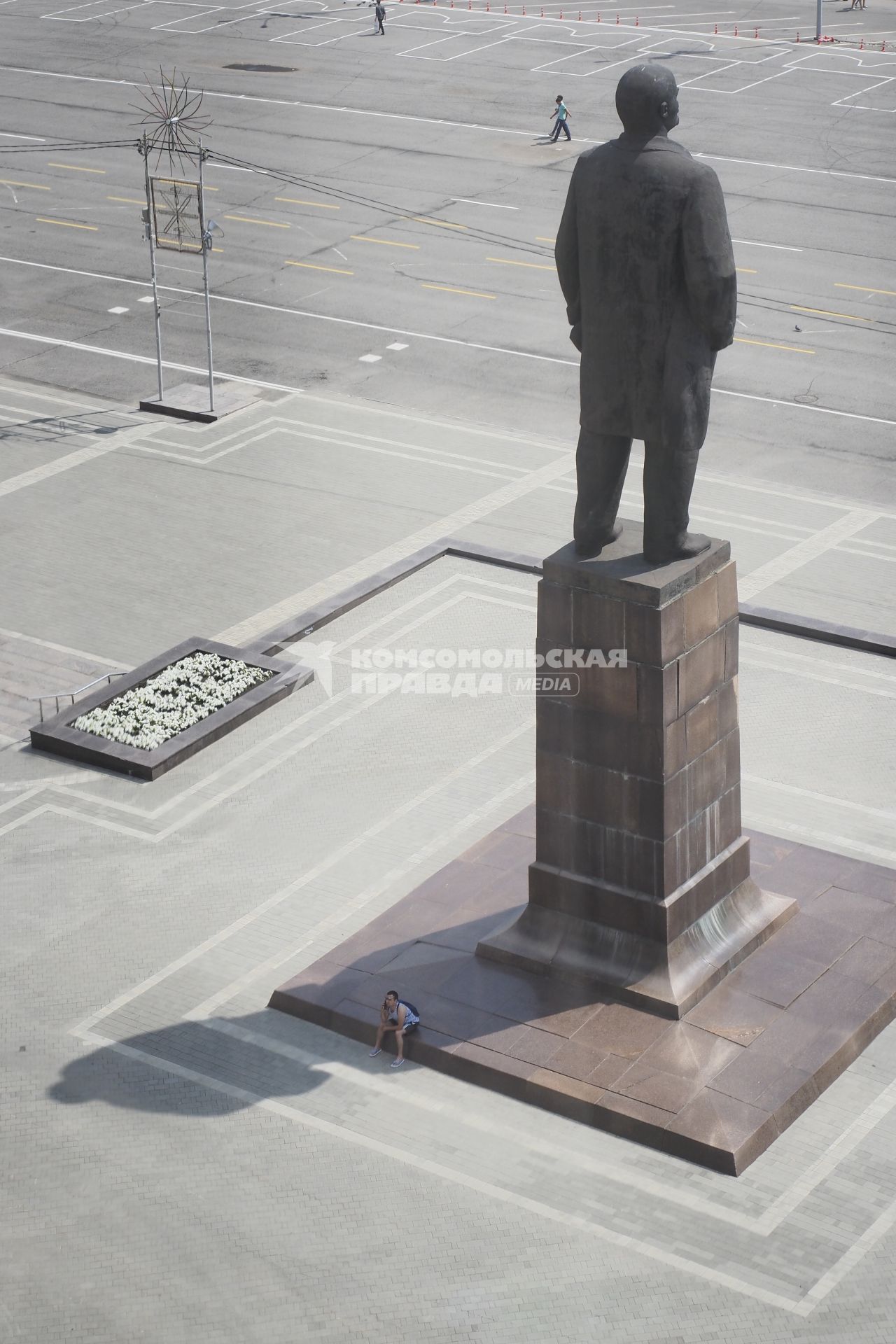 Тула. Мужчина сидит на постаменте в тени памятника Ленину.