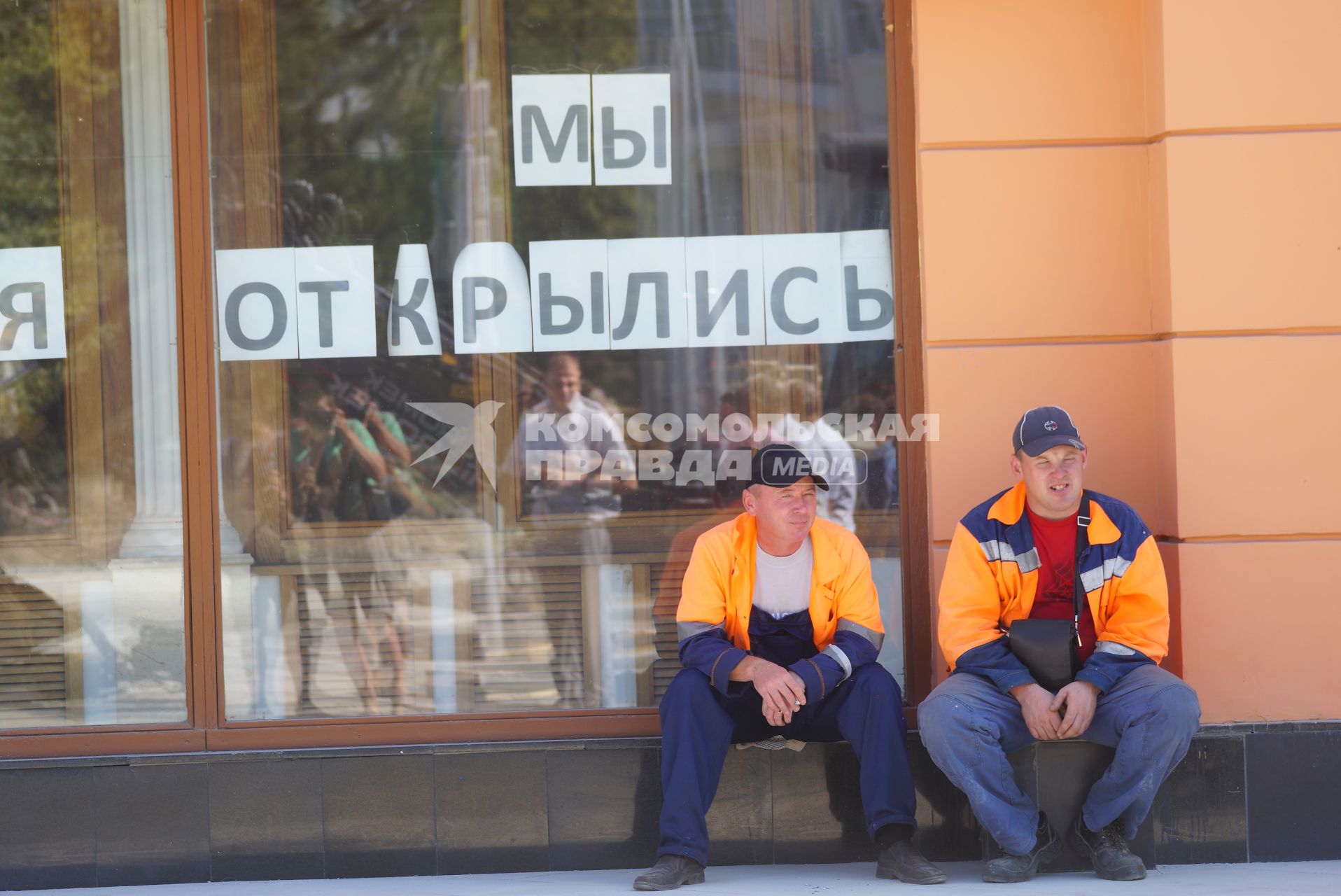 Екатеринбург. Рабочие сидят у окна с надписью \'Мы открылись\'