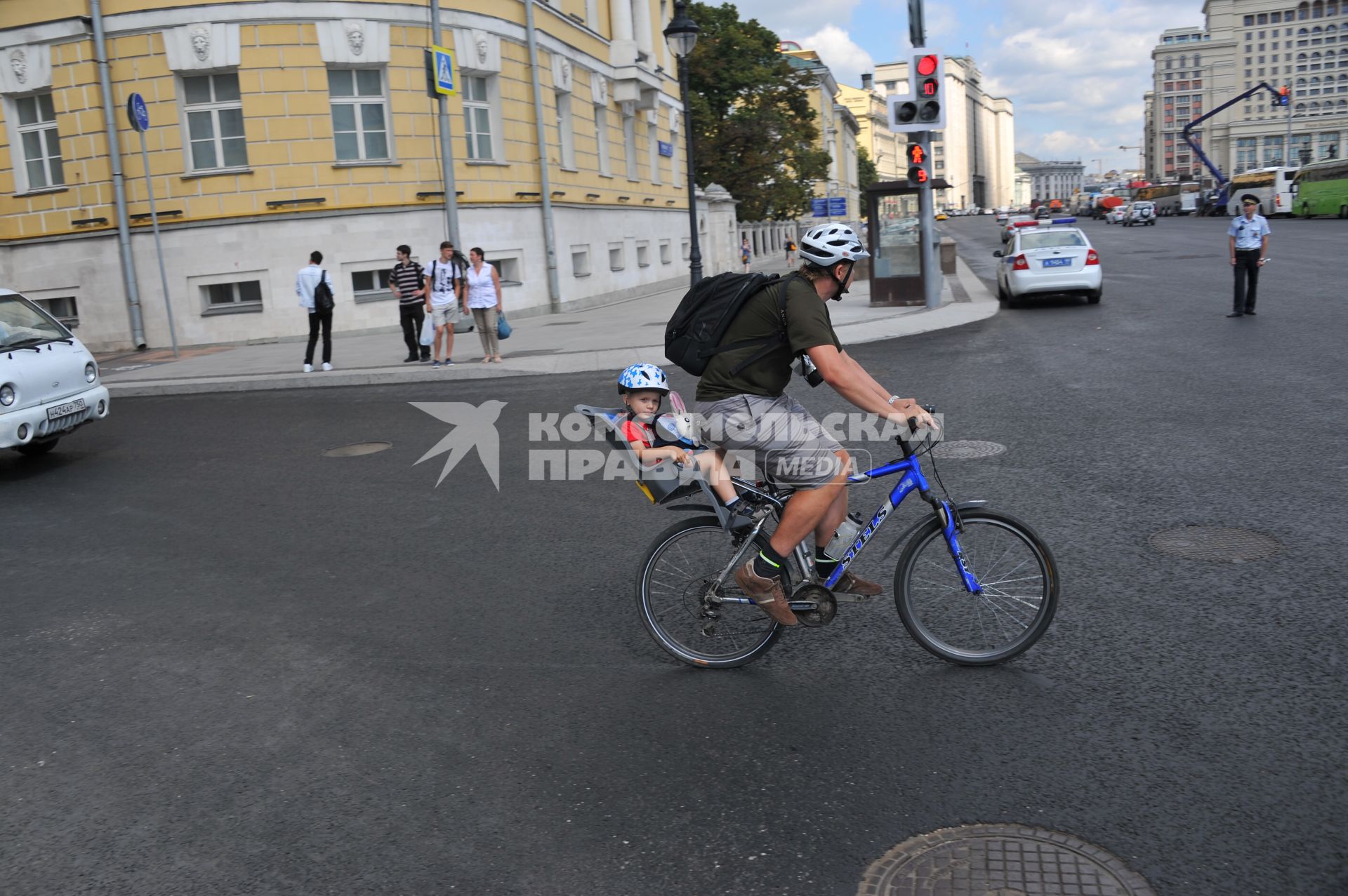 Москва.  Мужчина везет ребенка на велосипеде по Моховой улице.