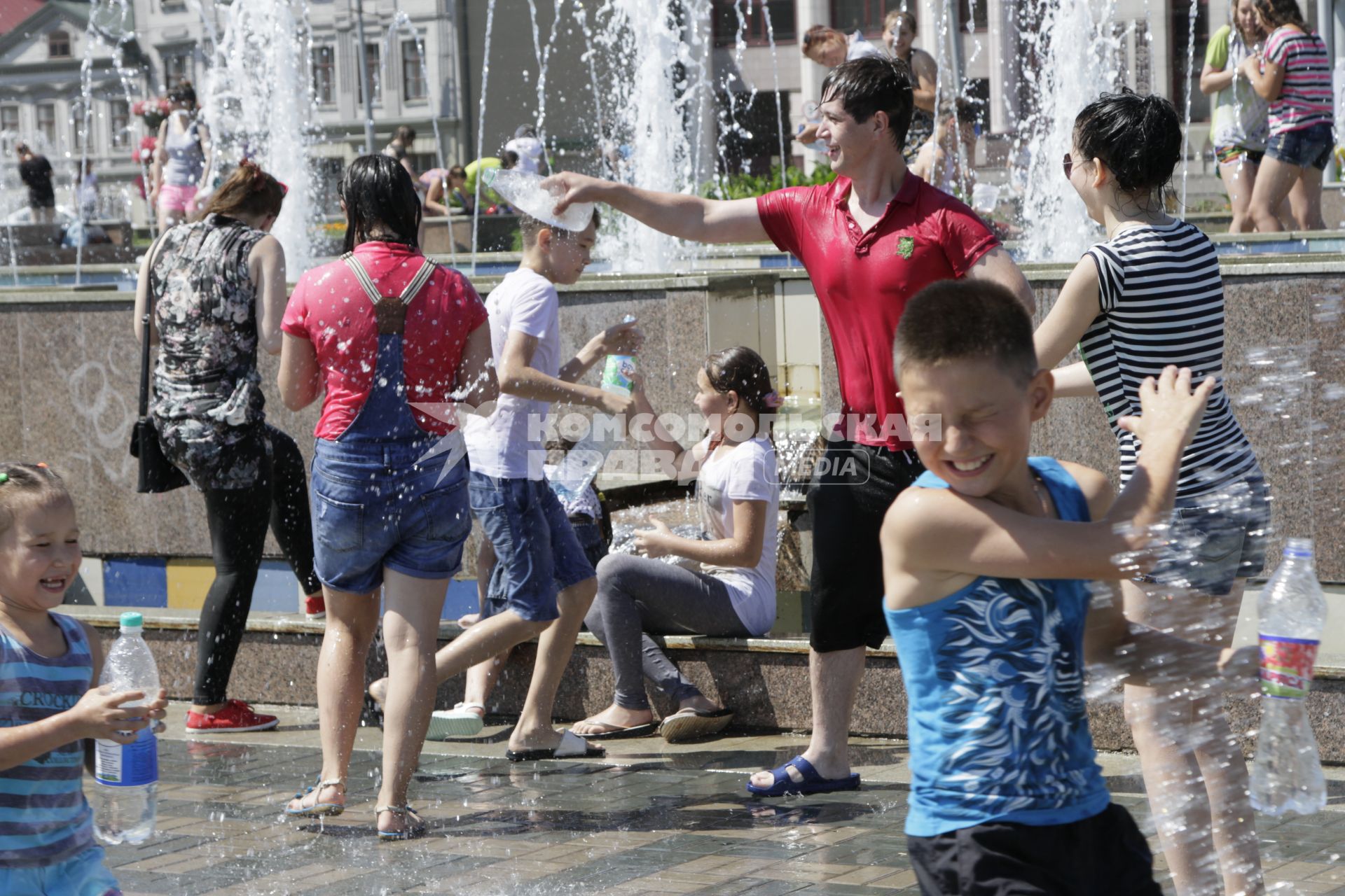 Казань. Молодые люди  обливают друг друга  водой из фонтана.