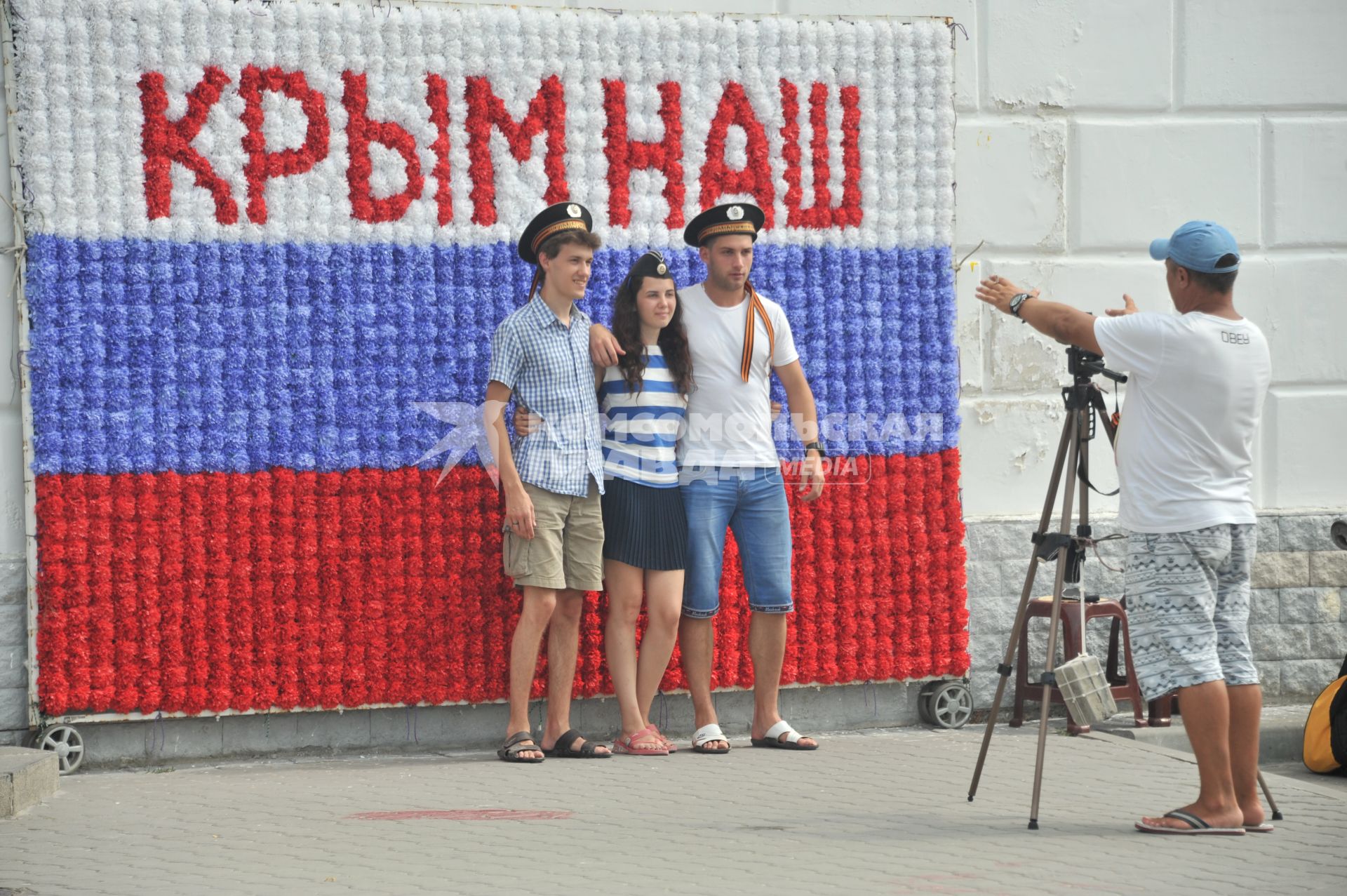 Крым, Севастополь. Молодые люди фотографируются на фоне флага РФ.