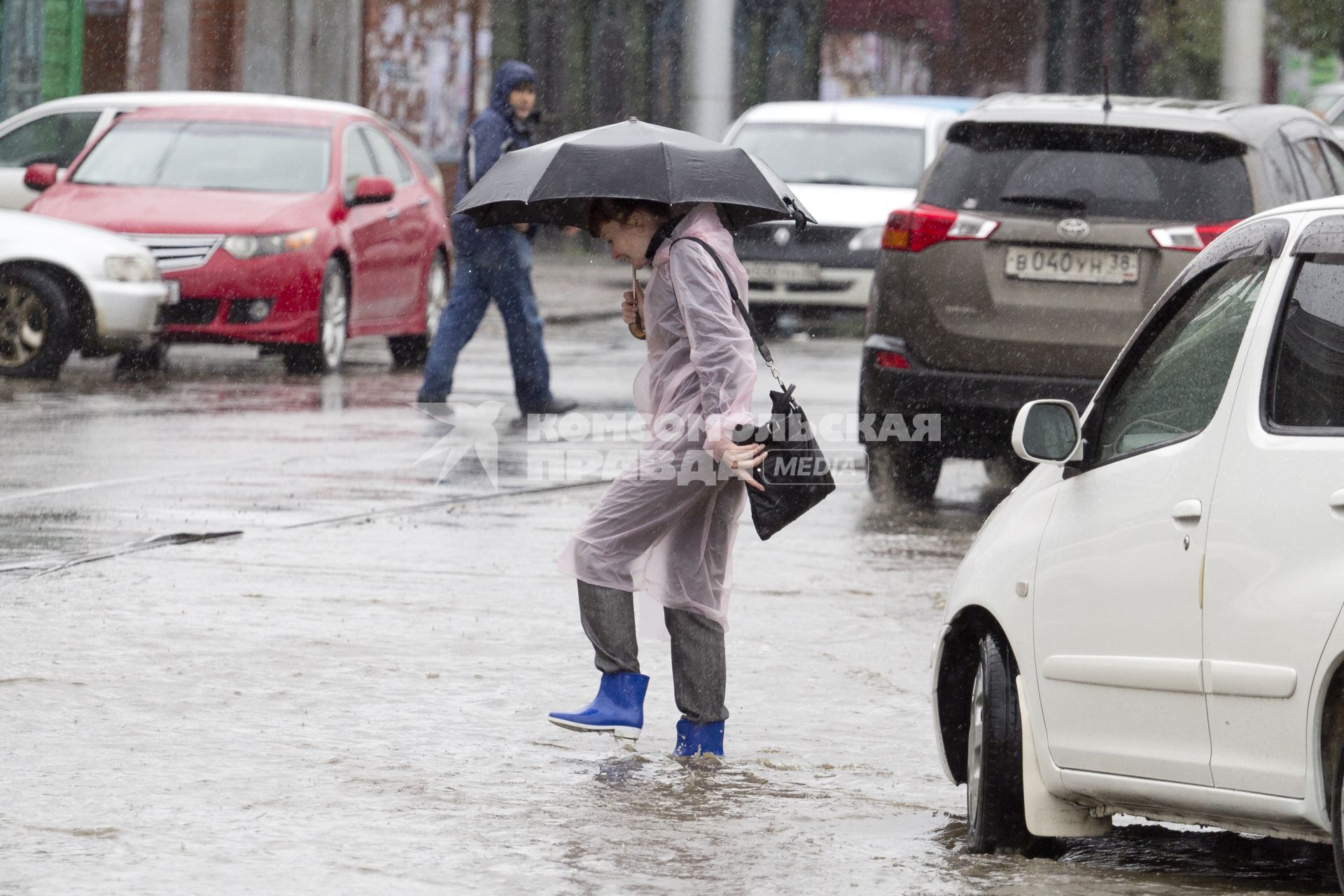 Иркутск. Женщина переходит дорогу во время дождя.