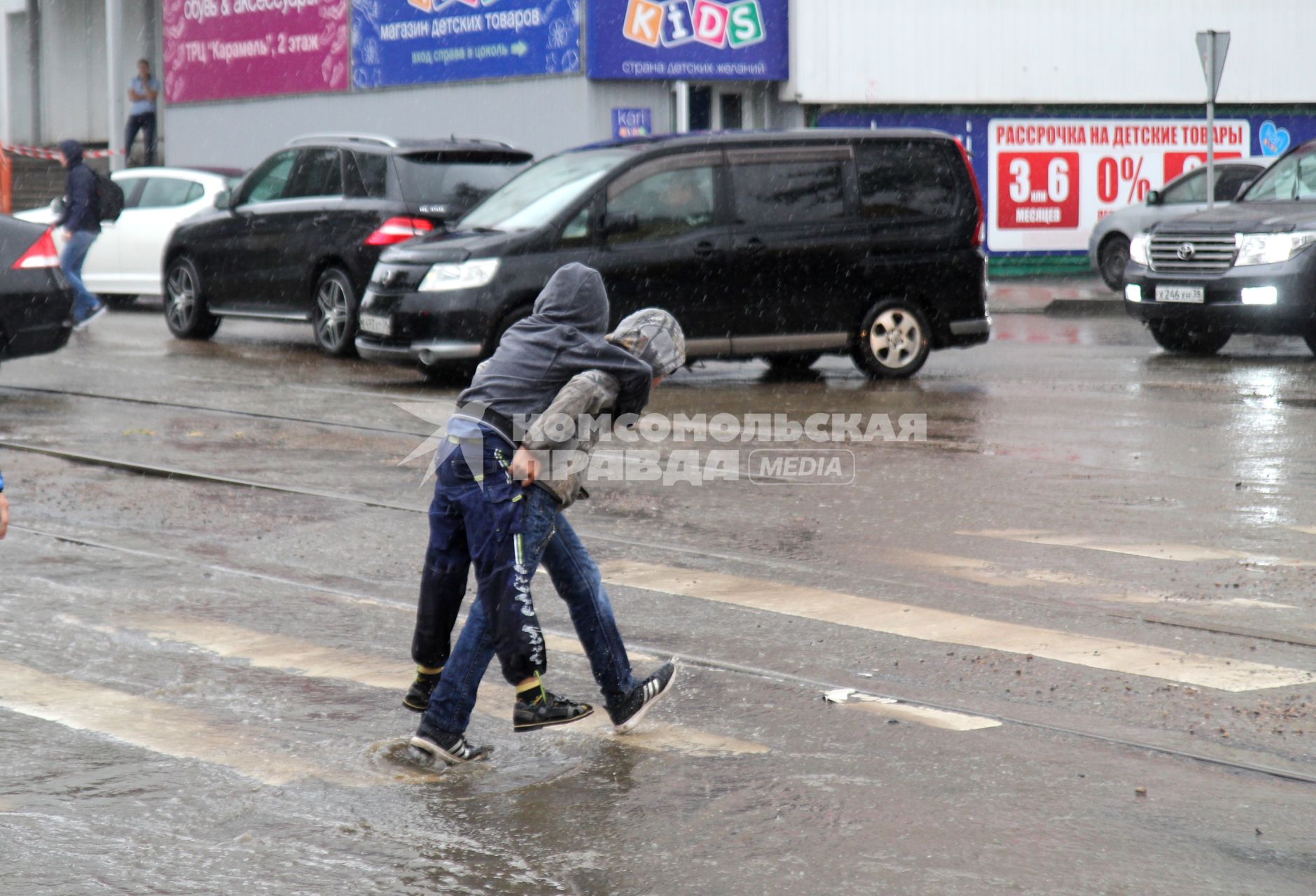 Иркутск. Дети идут по пешеходному переходу во время дождя.