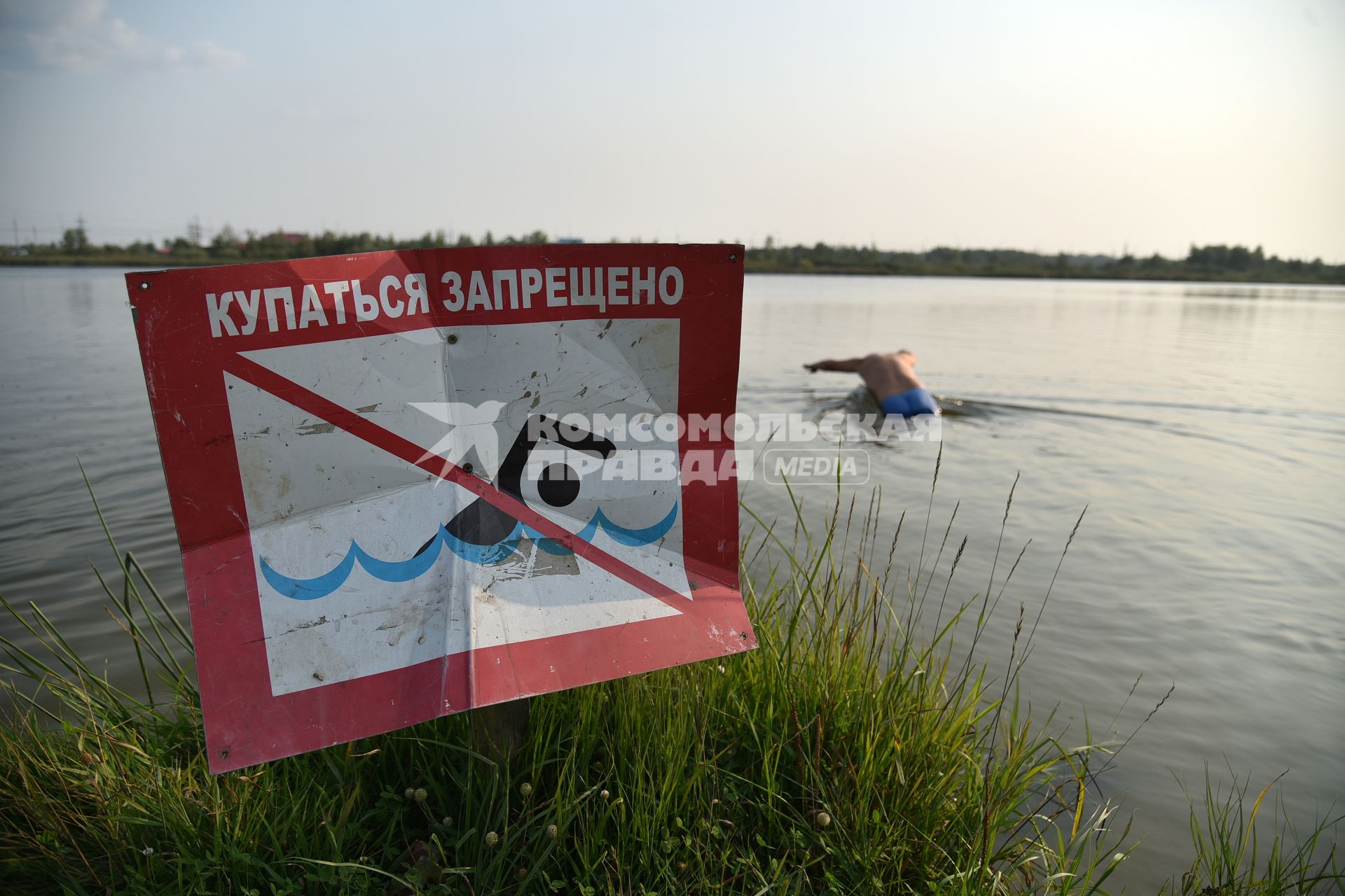 Новосибирск. Мужчина купается в озере возле знака `Купаться запрещено`.