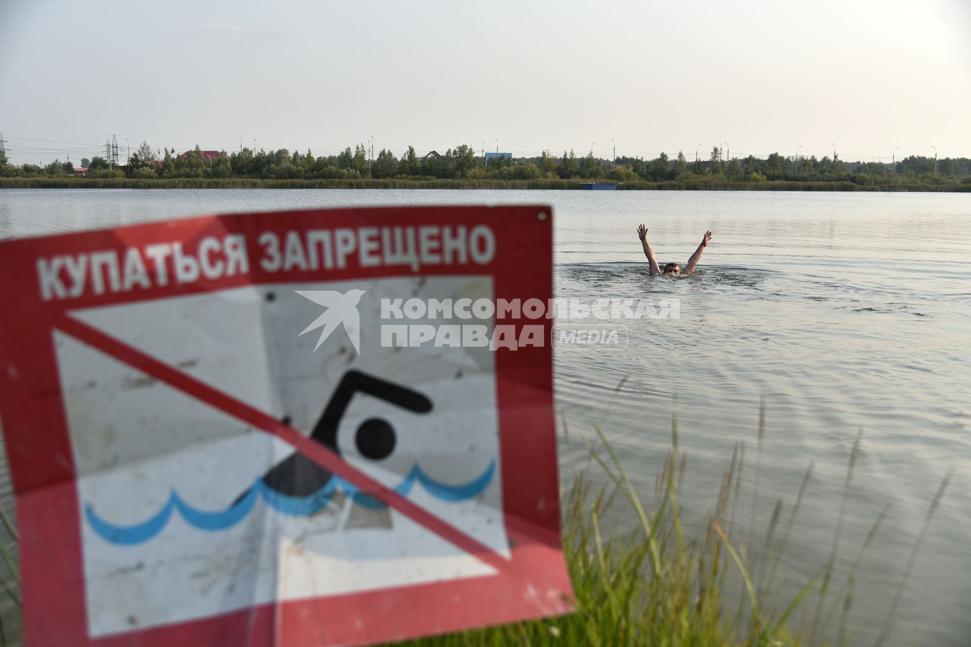 Новосибирск. Мужчина купается в озере возле знака `Купаться запрещено`.