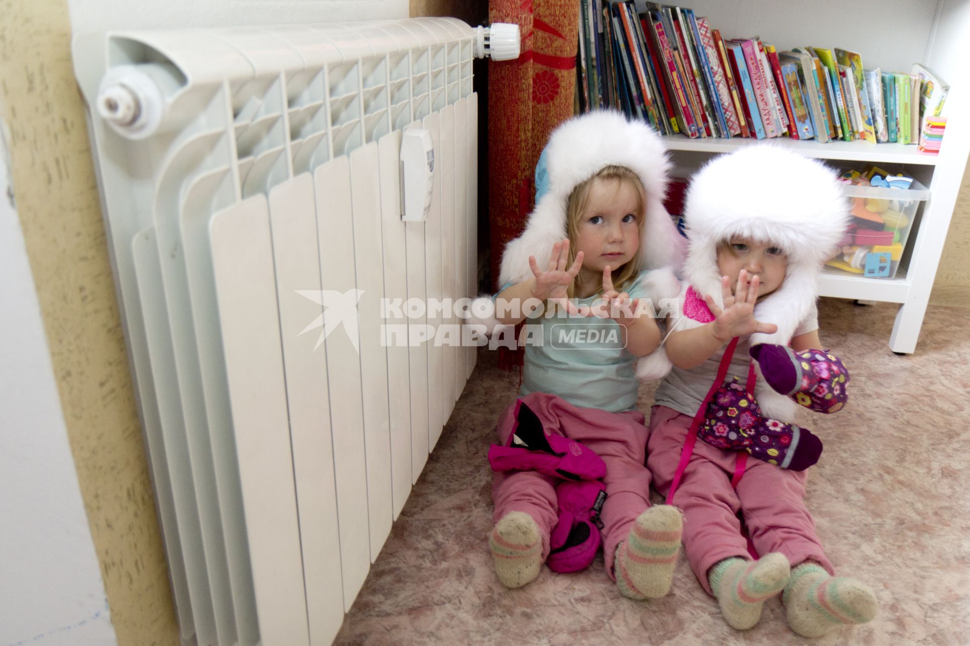 Иркутск. Девочки греются у батареи в холодной квартире.