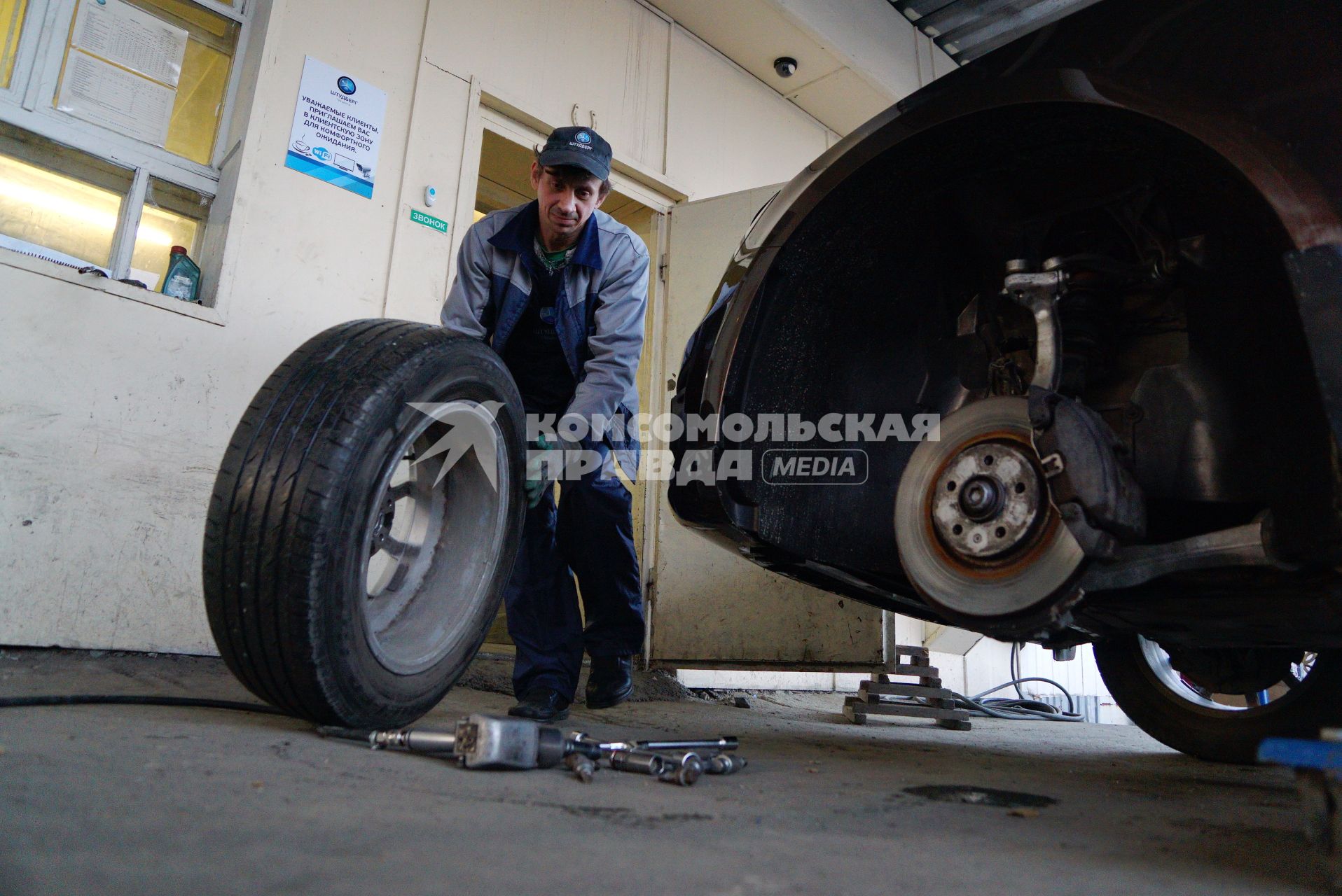 Екатеринбург. Сотрудник шиномонтажной мастерской меняет автомобильное колесо.