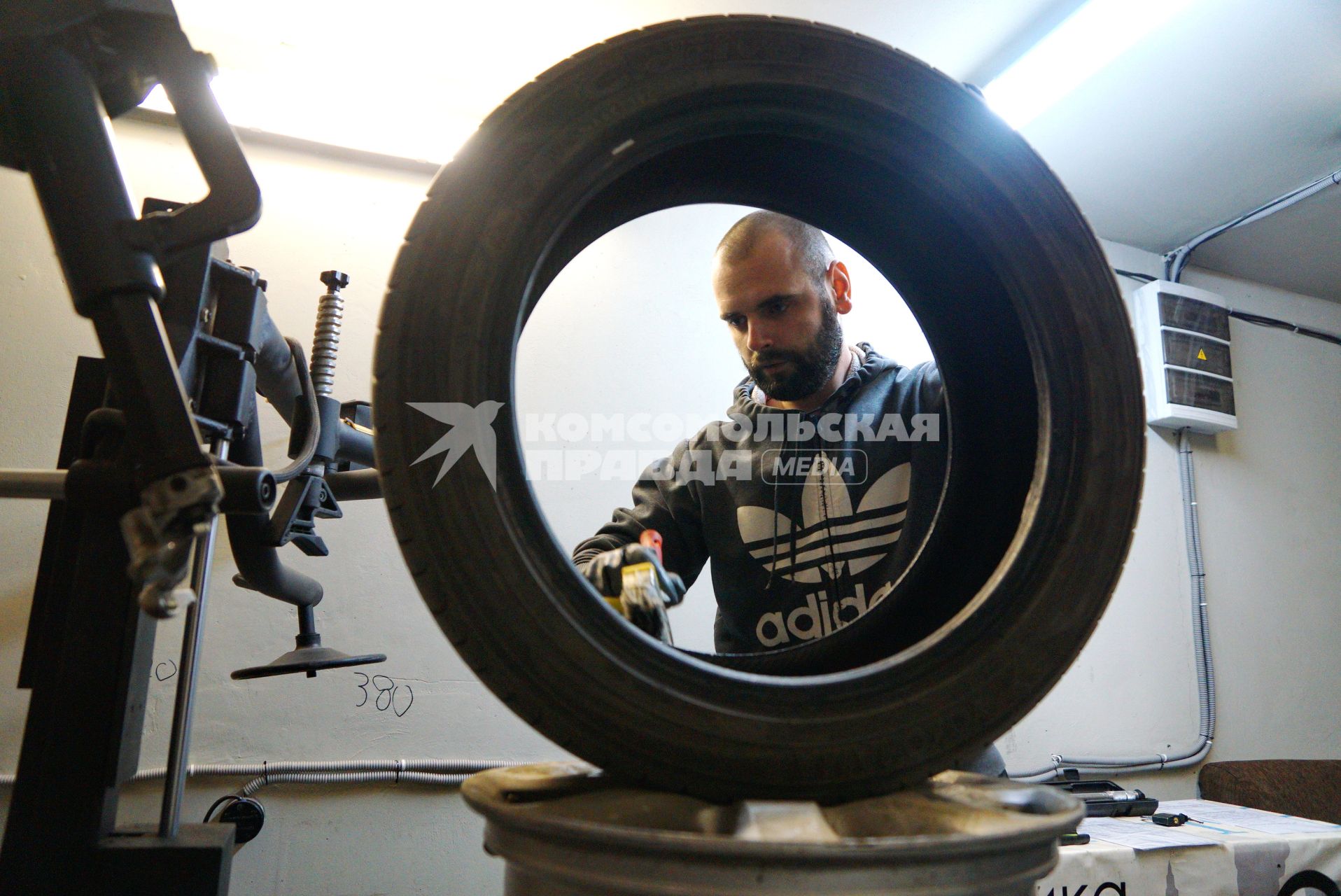 Екатеринбург. Сотрудник шиномонтажной мастерской меняет автомобильное колесо.