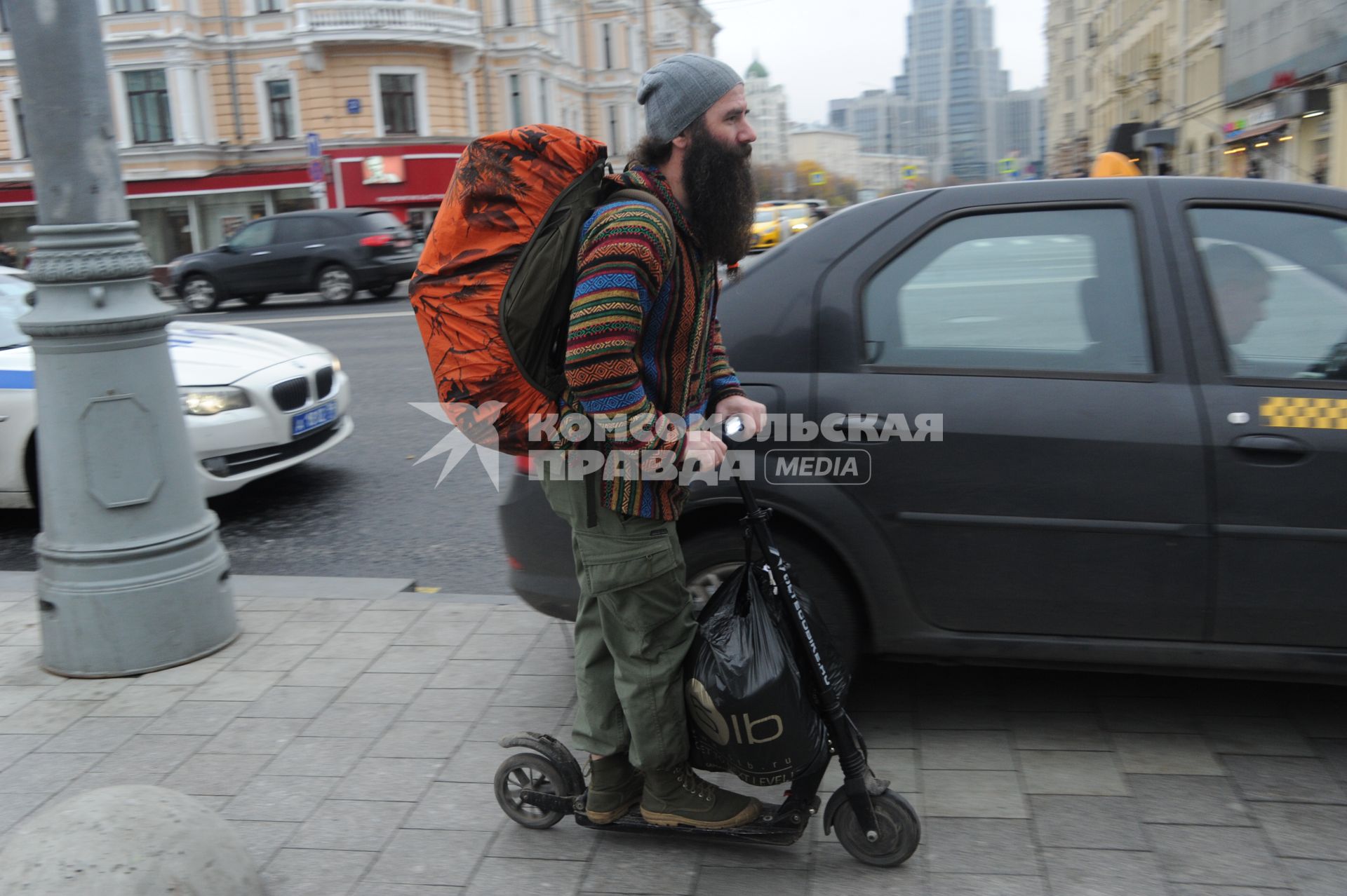 Москва.  Мужчина едет на самокате по Тверской улице.