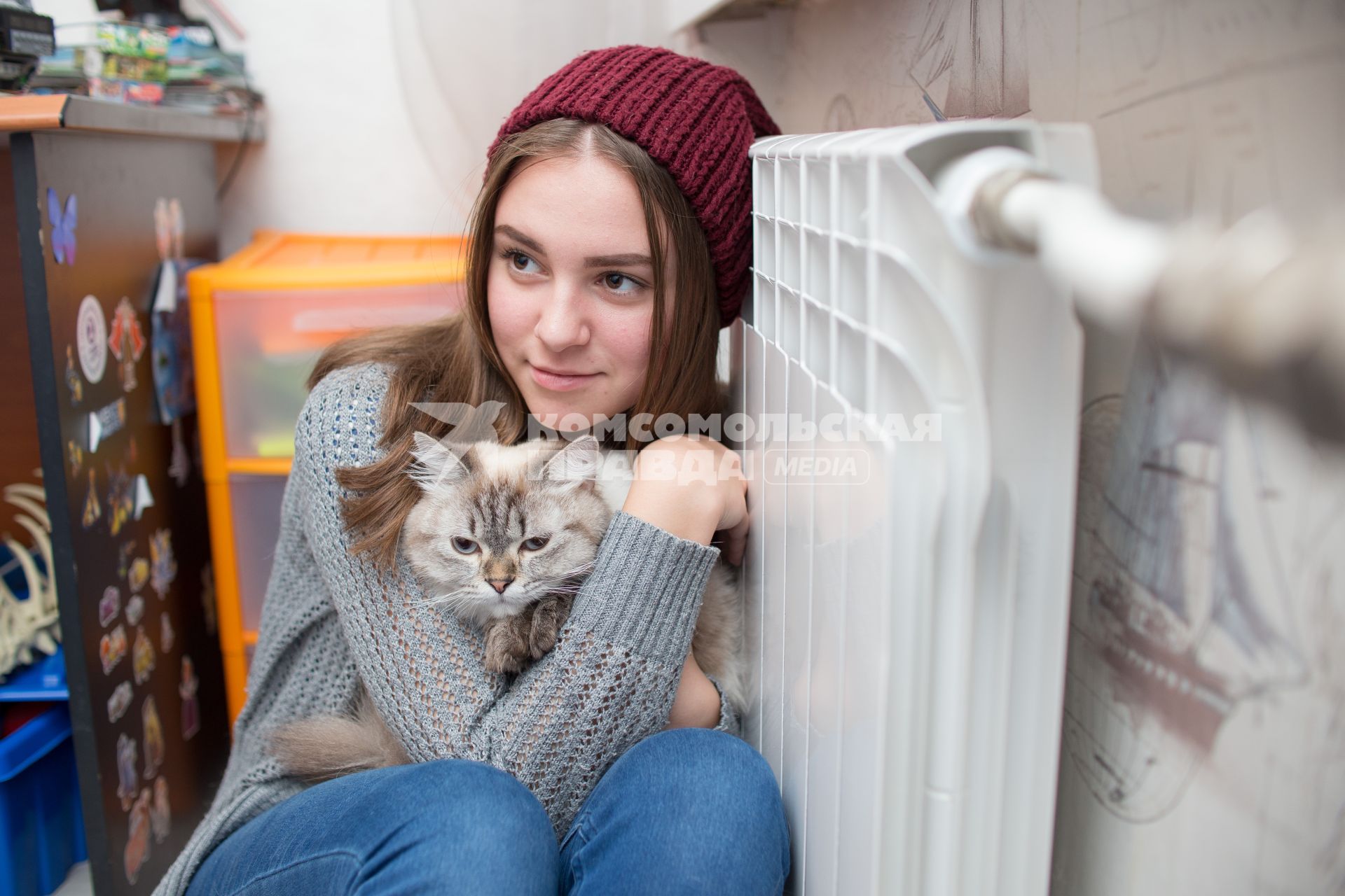 Челябинск.  Девушка с кошкой  сидит возле батареи центрального отопления.