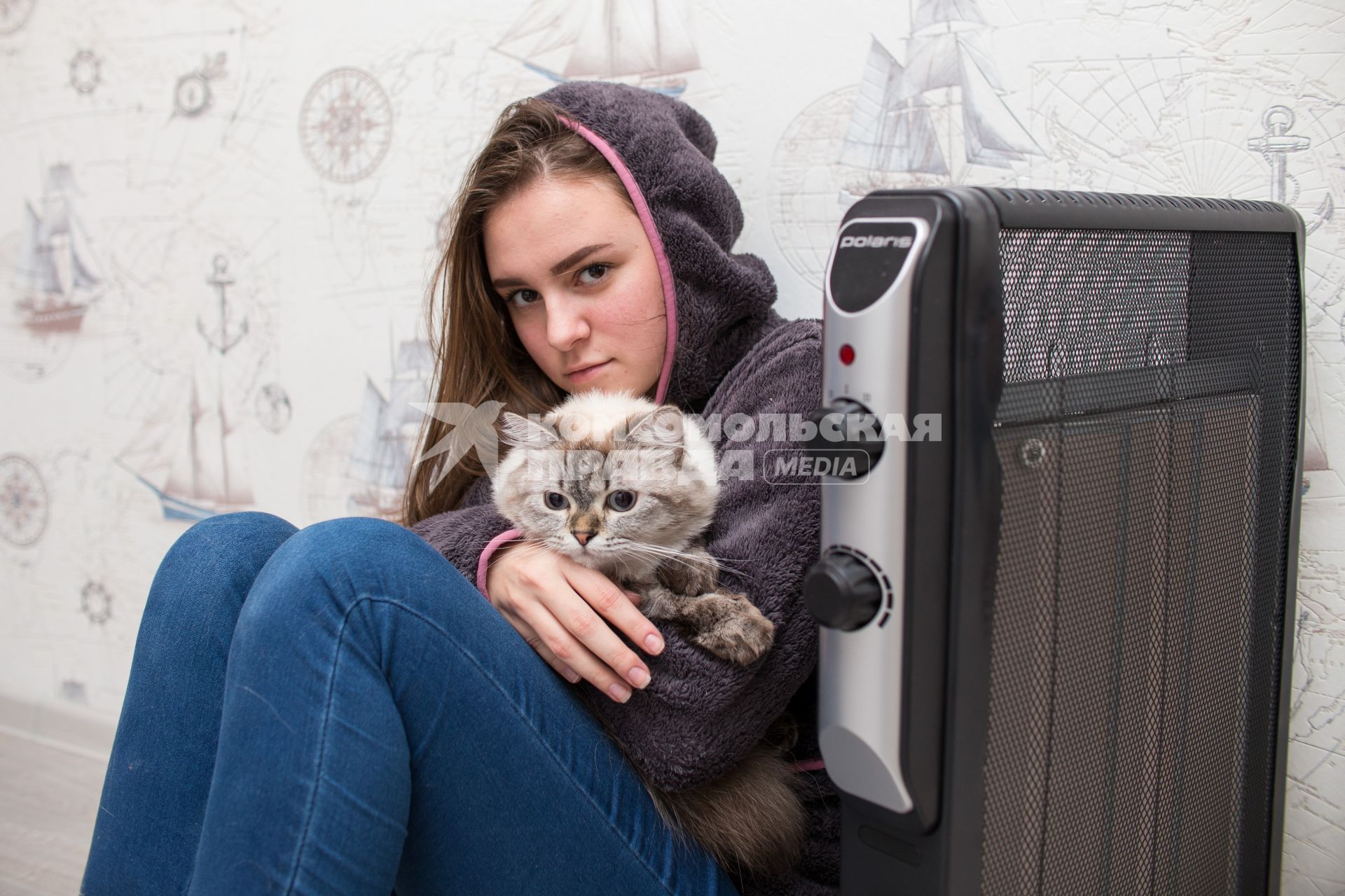 Челябинск.  Девушка с кошкой  сидит возле  обогревателя.