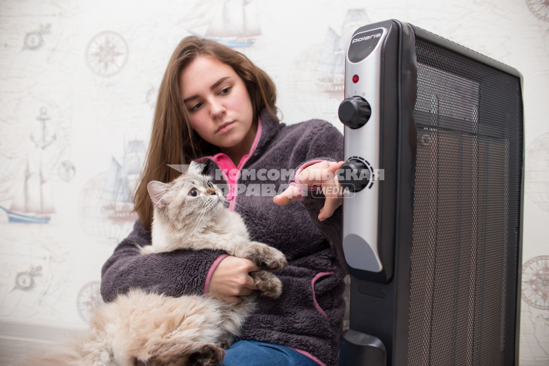 Челябинск.  Девушка с кошкой  сидит возле  обогревателя.
