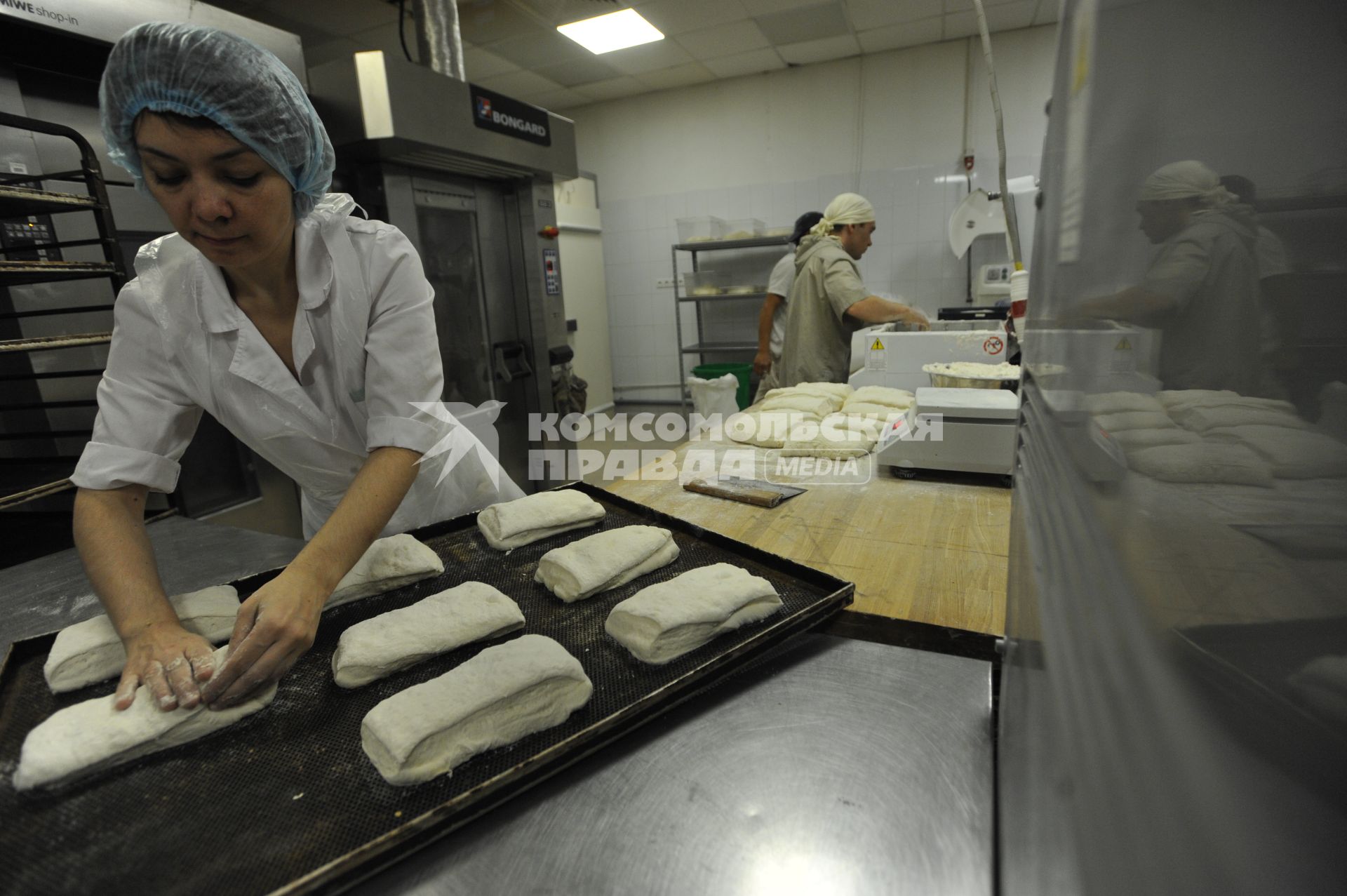 Зеленоград. Работница  пекарни укладывает на противень заготовки для выпечки.