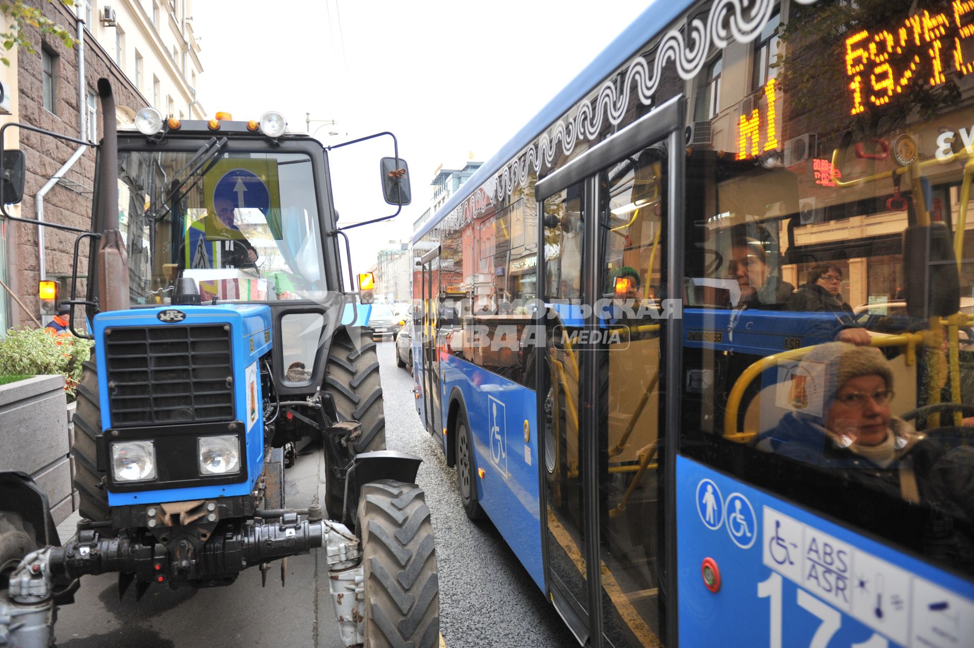 Москва.  Трактор и автобус  маршрута М1 на Тверской улице.