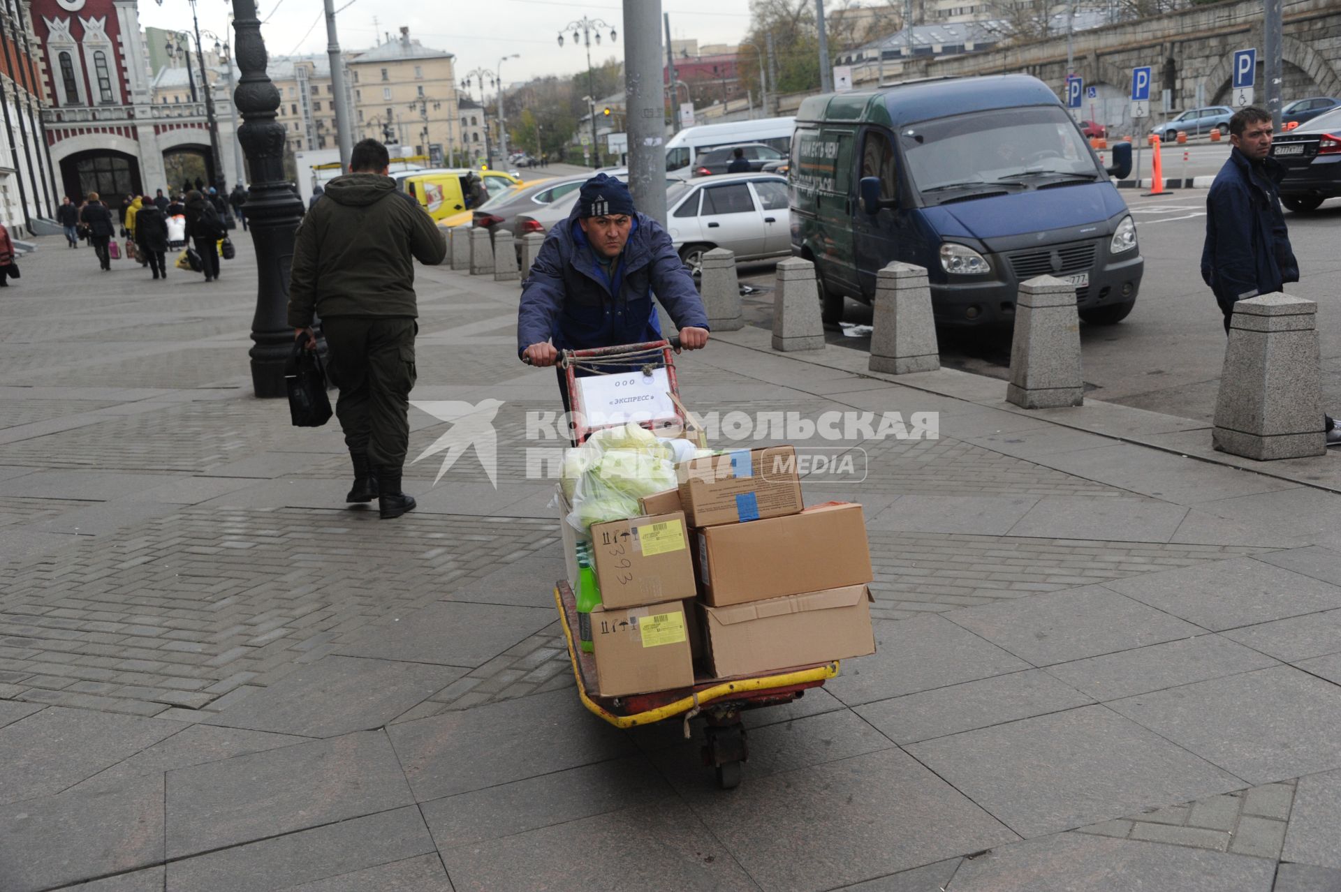 Москва.  Грузчик везет тележку с коробками  рядом с Казанским вокзалом.