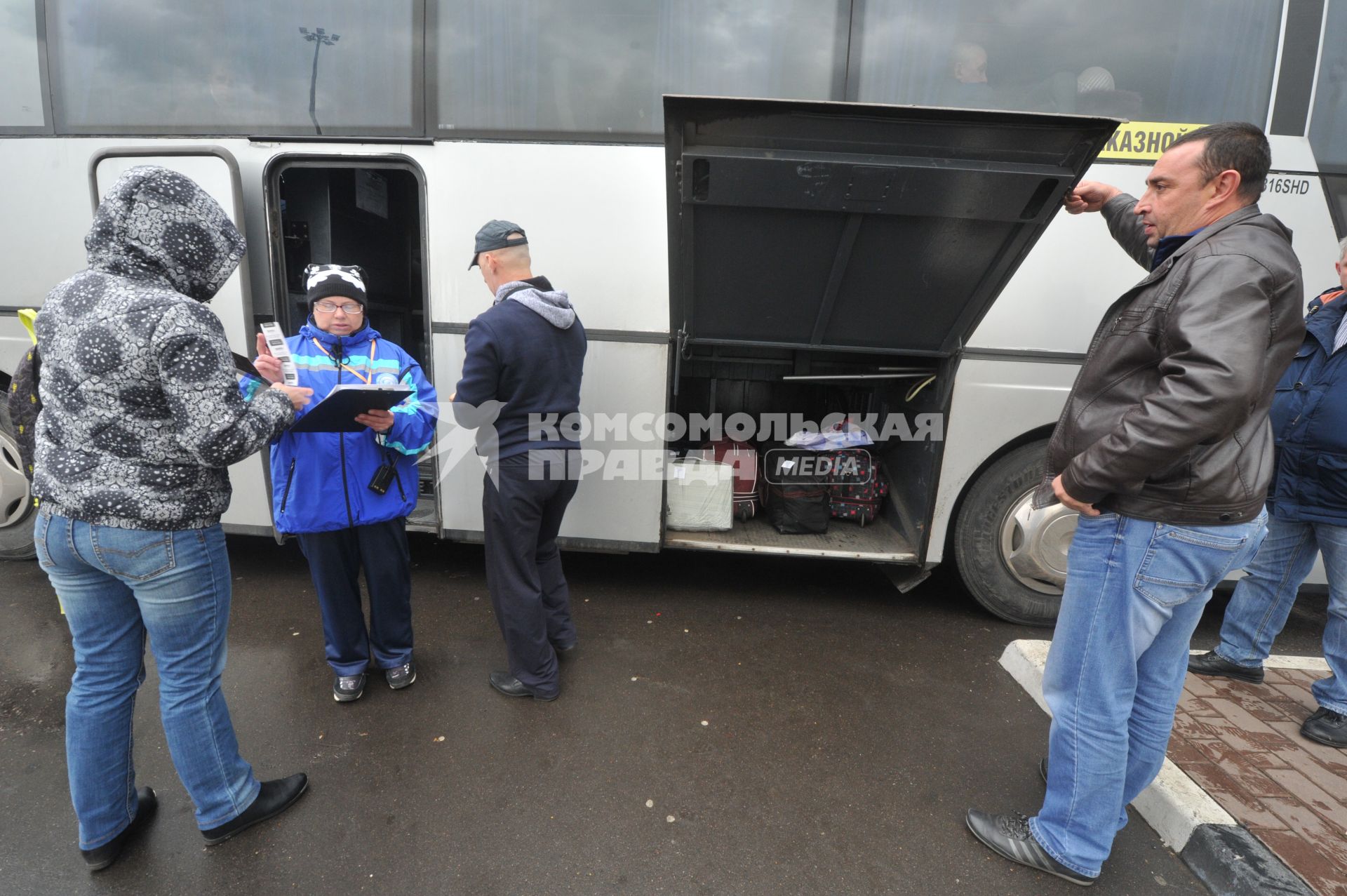 Москва.  Кондуктор проверяет билет у пассажира перед отправлением автобуса у здания международного автовокзала `Южные ворота` в Люблино.